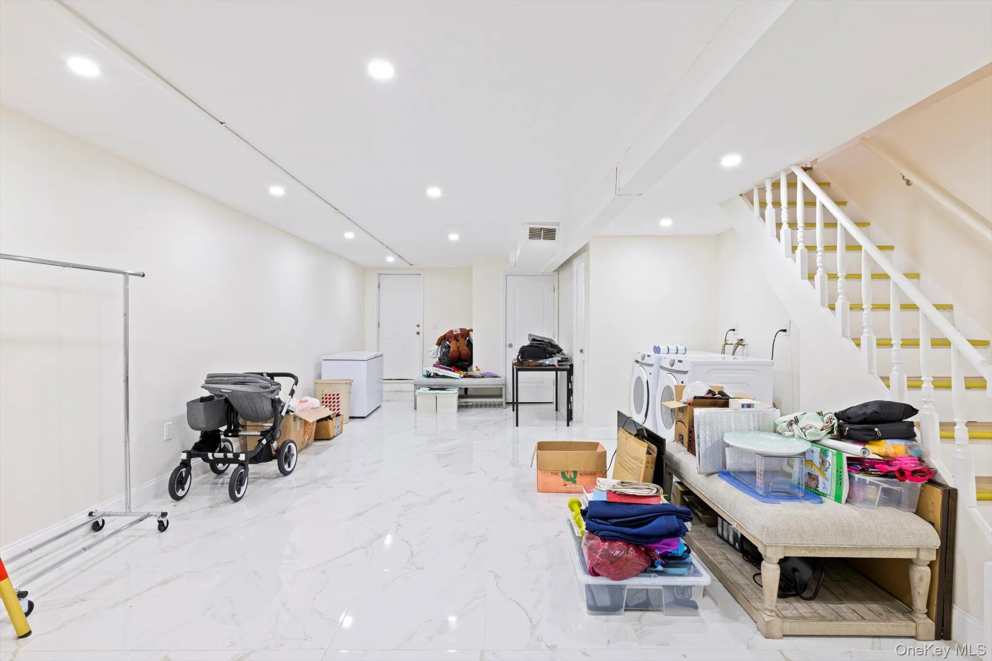 Playroom with recessed lighting, washer and dryer, and light marble finish flooring Playroom with recessed lighting, washer and dryer, and light marble finish flooring