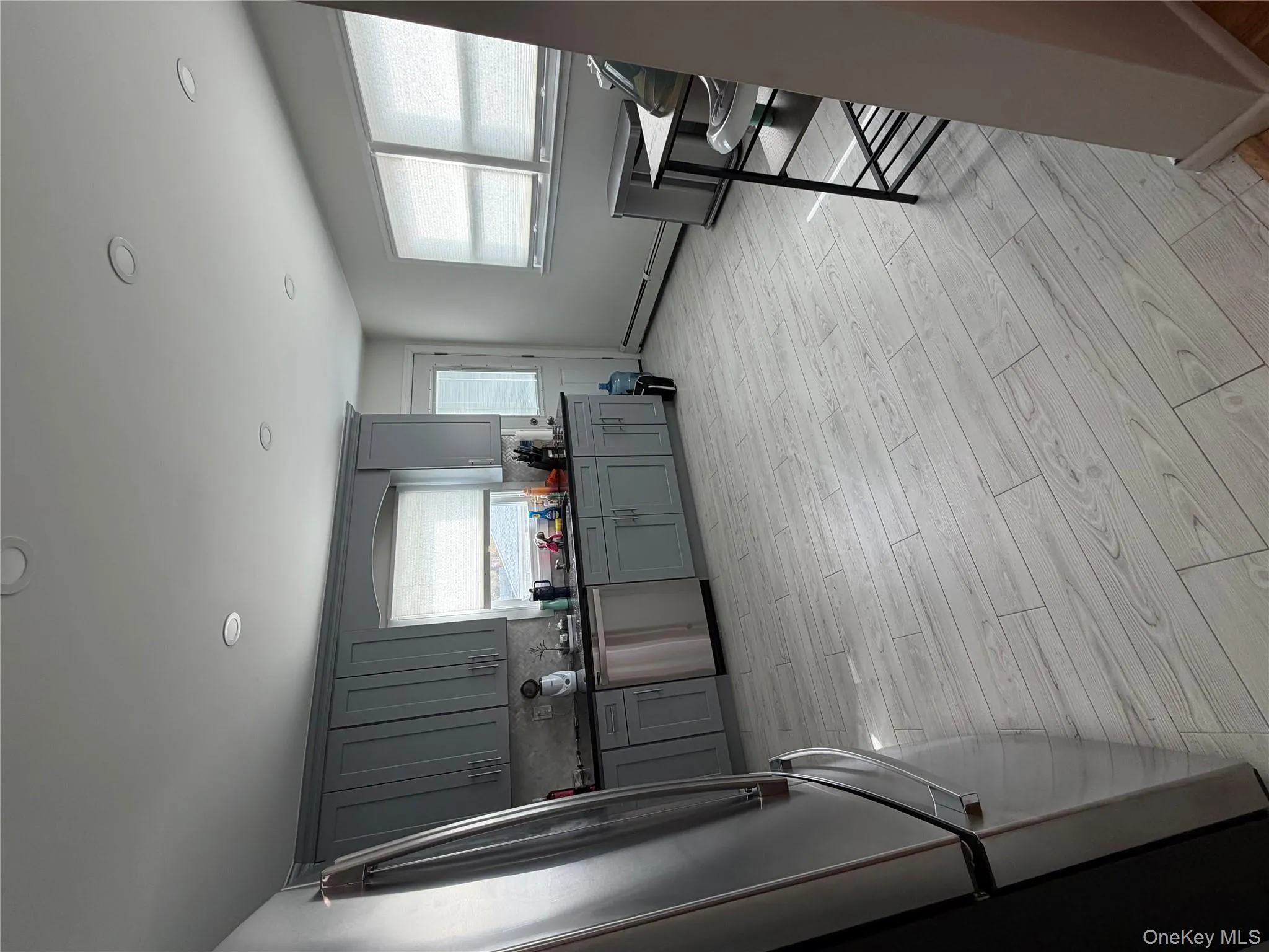 Kitchen featuring gray cabinets, wood floors, refrigerator, stainless steel dishwasher, and recessed lighting Kitchen featuring gray cabinets, wood floors, refrigerator, stainless steel dishwasher, and recessed lighting