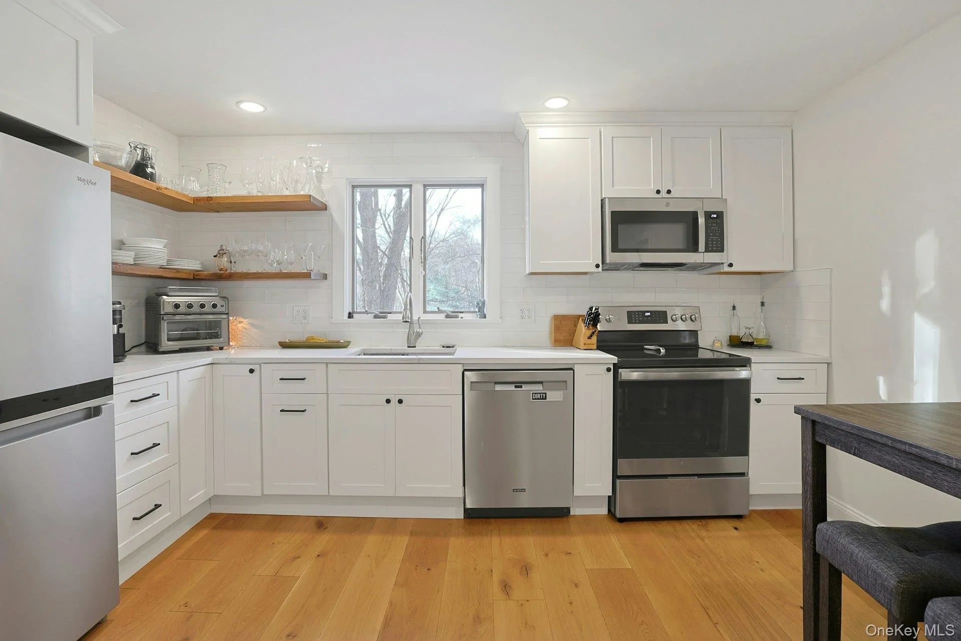 Kitchen featuring stainless steel appliances with open shelves, white cabinets, light countertops, recessed lighting, and decorative backsplash Kitchen featuring stainless steel appliances with open shelves, white cabinets, light countertops, recessed lighting, and decorative backsplash
