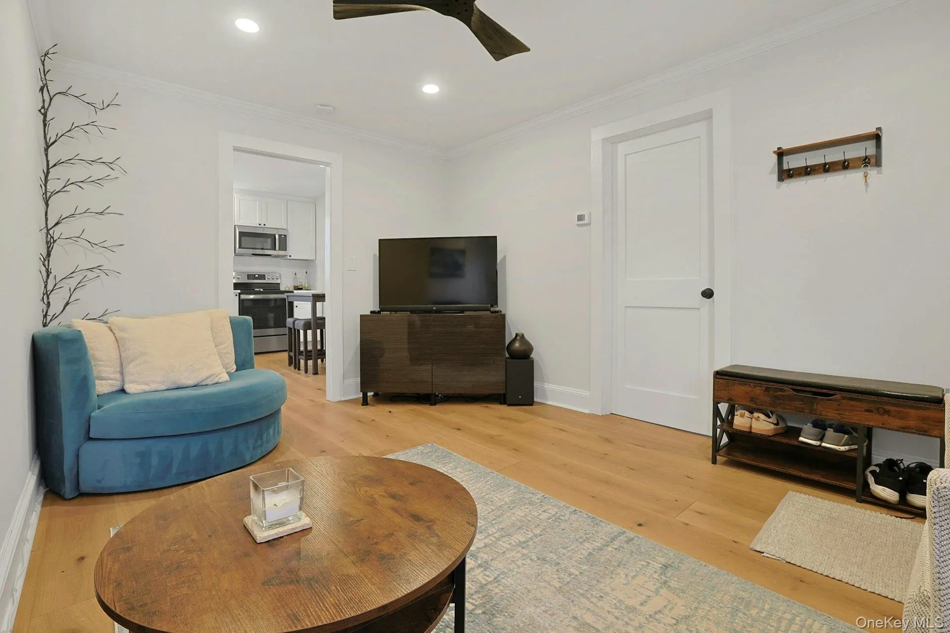 Living room with crown molding, light wood finished floors, recessed lighting, and a ceiling fan Living room with crown molding, light wood finished floors, recessed lighting, and a ceiling fan