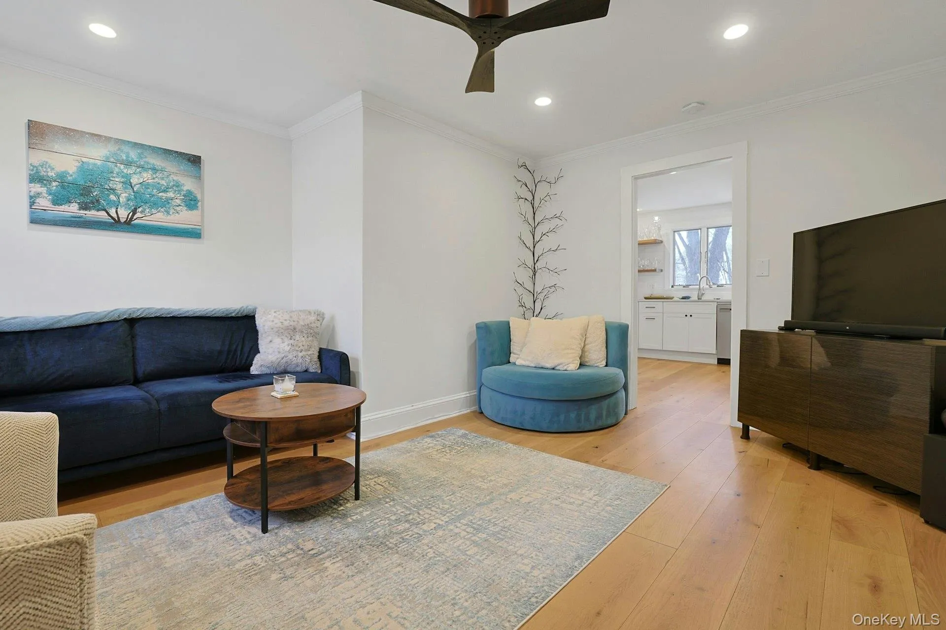 Living room with crown molding, light wood finished floors, recessed lighting, and a ceiling fan Living room with crown molding, light wood finished floors, recessed lighting, and a ceiling fan