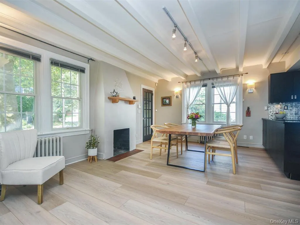 Dining space with beamed ceiling, radiator, light wood-type flooring, a fireplace, and rail lighting Dining space with beamed ceiling, radiator, light wood-type flooring, a fireplace, and rail lighting