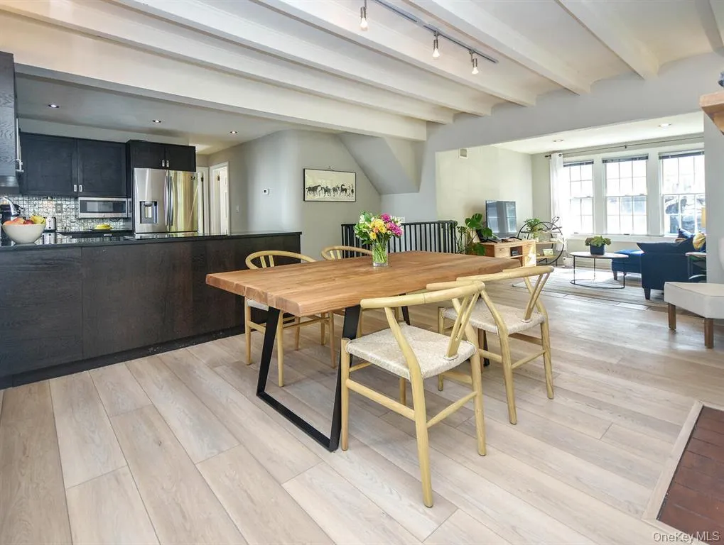 Dining area with beamed ceiling, light wood-style flooring, and track lighting Dining area with beamed ceiling, light wood-style flooring, and track lighting