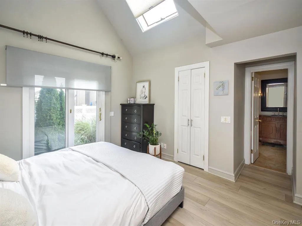 Bedroom with a skylight, access to outside, light wood-type flooring, and vaulted ceiling Bedroom with a skylight, access to outside, light wood-type flooring, and vaulted ceiling
