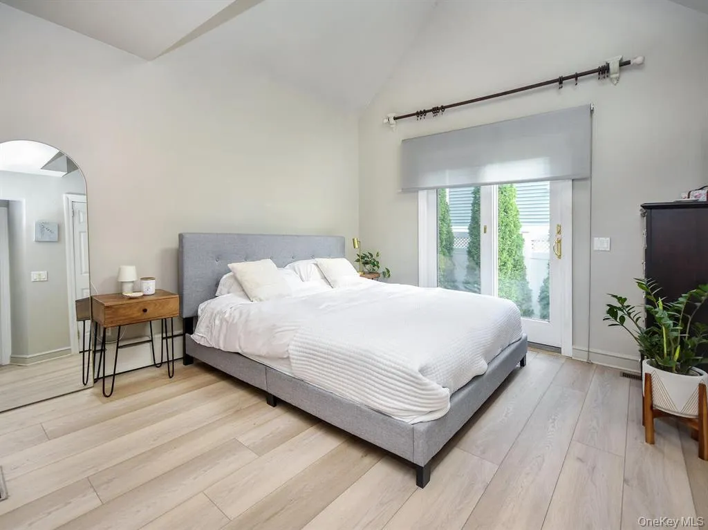 Bedroom with access to outside, light wood-type flooring, arched walkways, and high vaulted ceiling Bedroom with access to outside, light wood-type flooring, arched walkways, and high vaulted ceiling