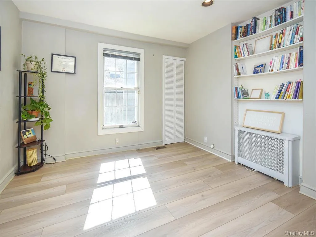 Empty room with radiator heating unit and light wood-style flooring Empty room with radiator heating unit and light wood-style flooring