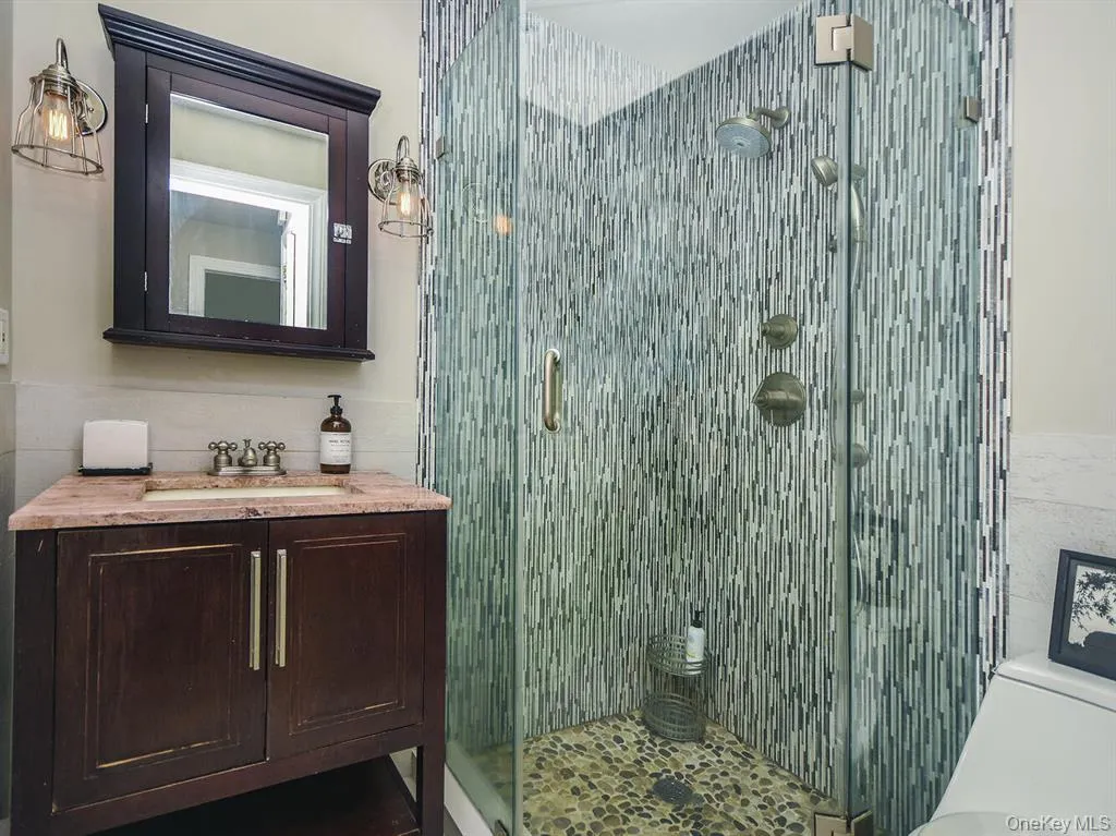 Full bathroom featuring vanity, a shower stall, and tile walls Full bathroom featuring vanity, a shower stall, and tile walls