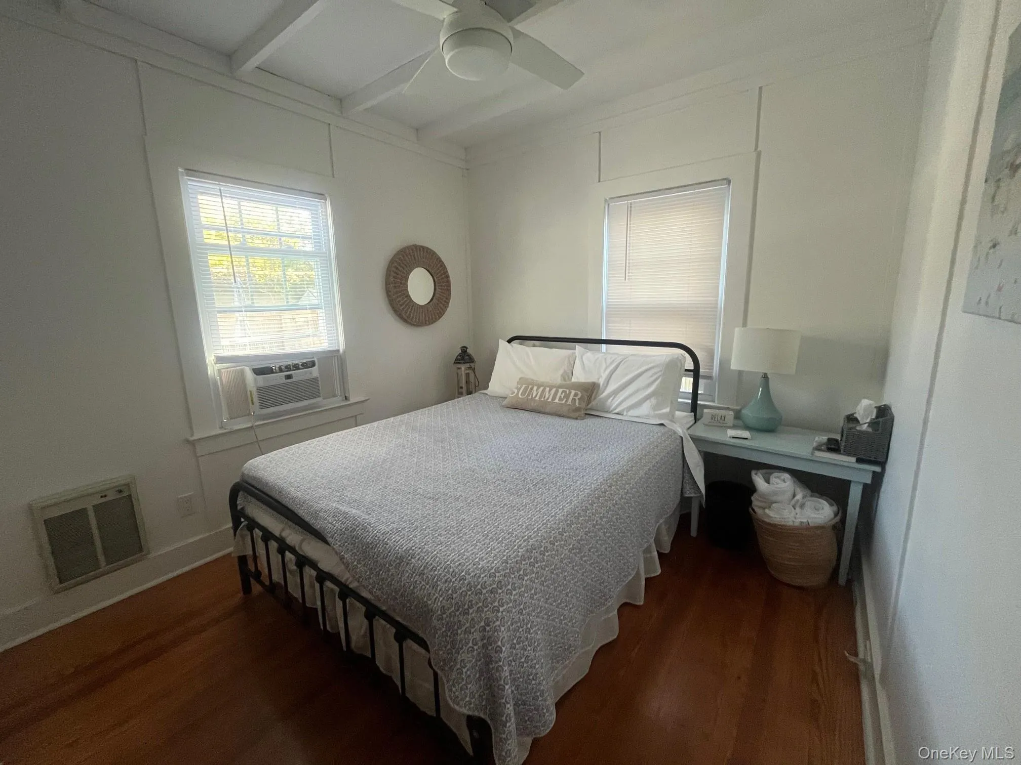 Bedroom featuring dark wood-style flooring, beam ceiling, ceiling fan, and cooling unit Bedroom featuring dark wood-style flooring, beam ceiling, ceiling fan, and cooling unit