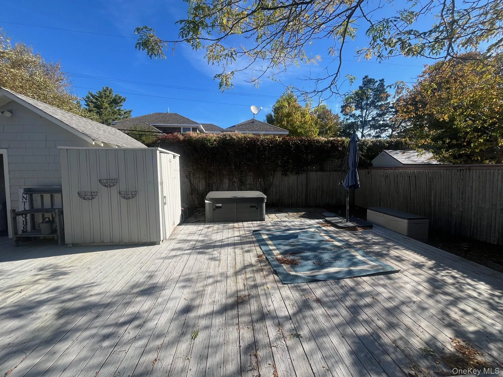 Wooden terrace featuring a fenced backyard, a storage shed, and a hot tub Wooden terrace featuring a fenced backyard, a storage shed, and a hot tub