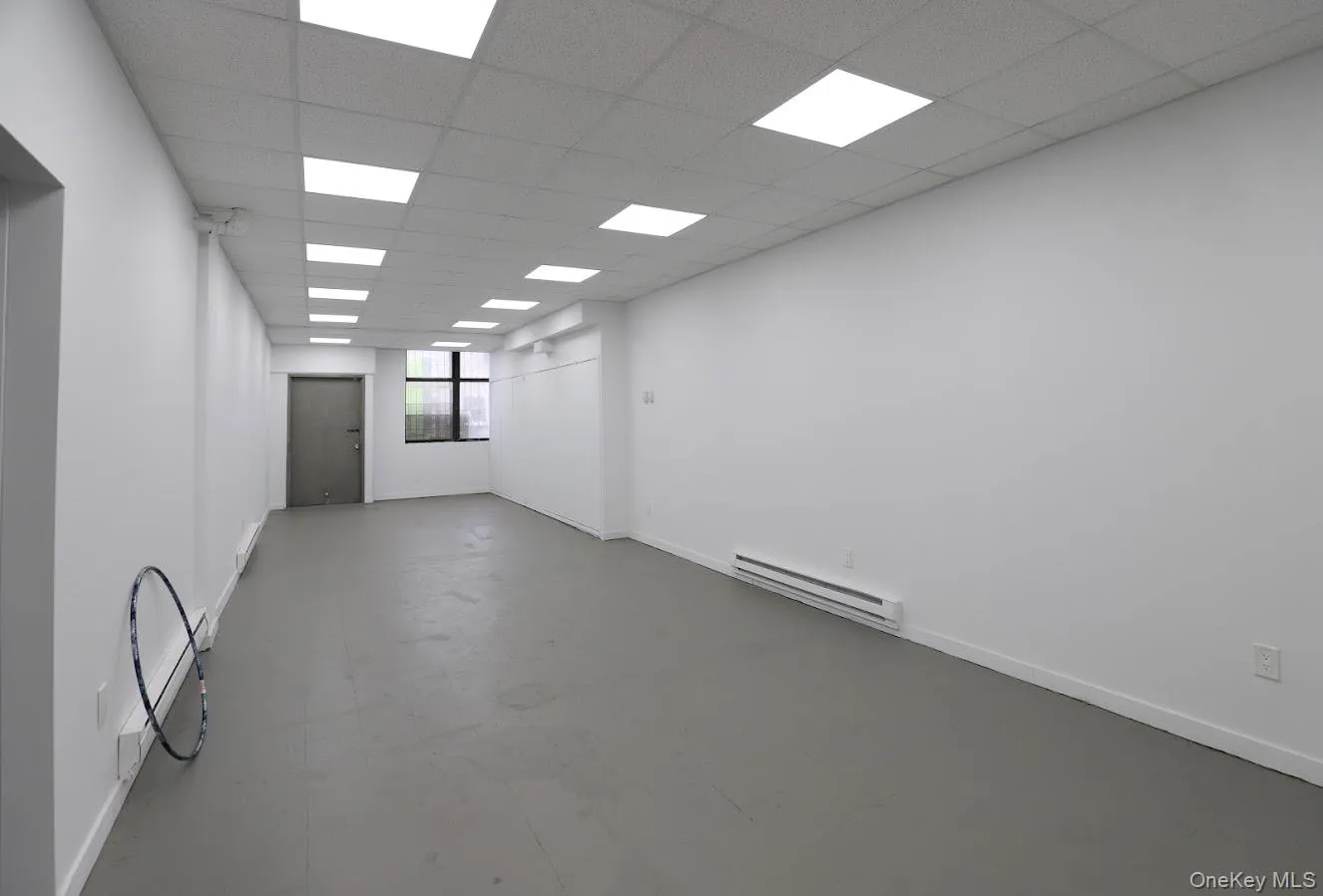 Spare room featuring a baseboard heating unit, a drop ceiling, and finished concrete floors Spare room featuring a baseboard heating unit, a drop ceiling, and finished concrete floors