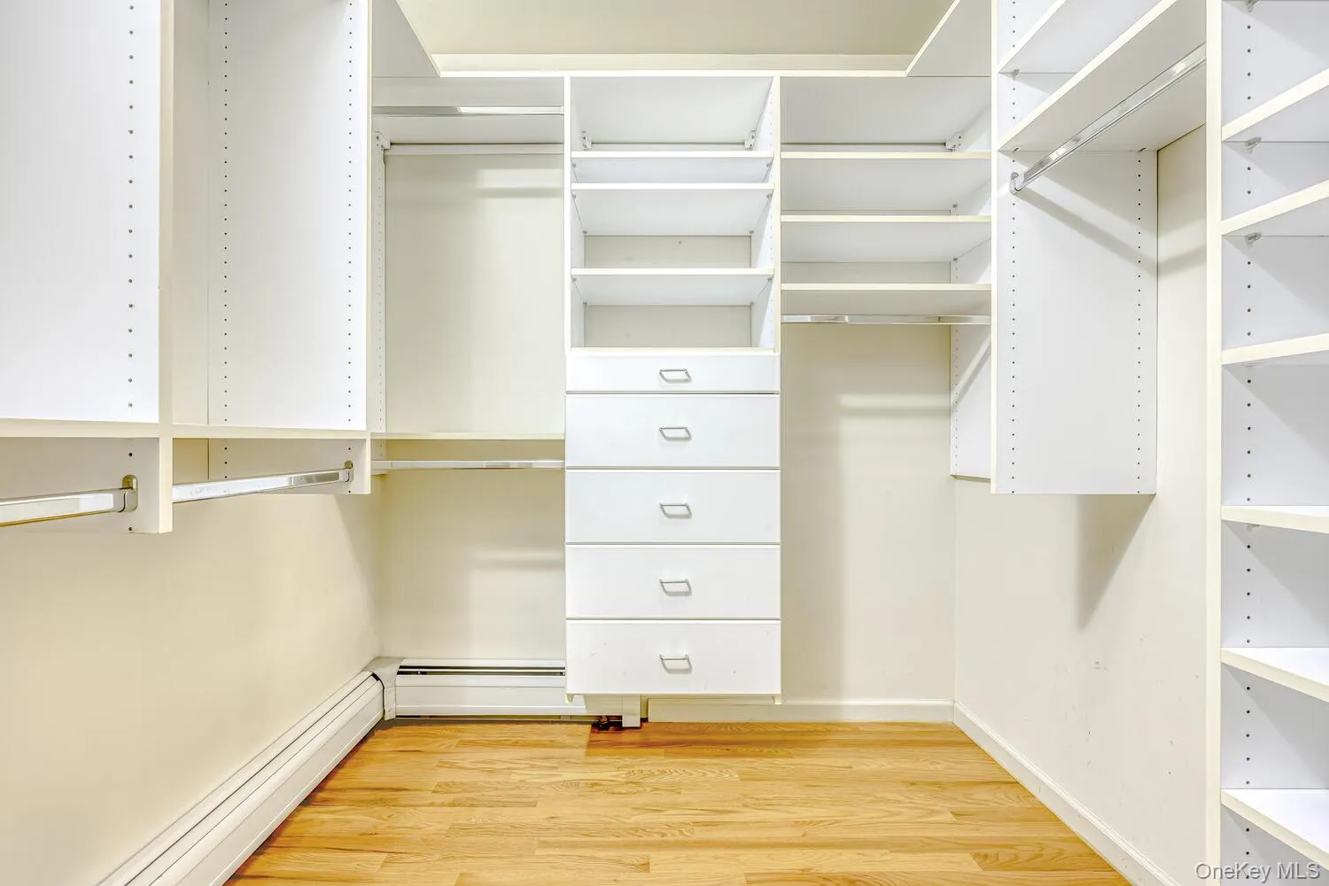 Spacious closet featuring light wood-style floors and a baseboard heating unit Spacious closet featuring light wood-style floors and a baseboard heating unit