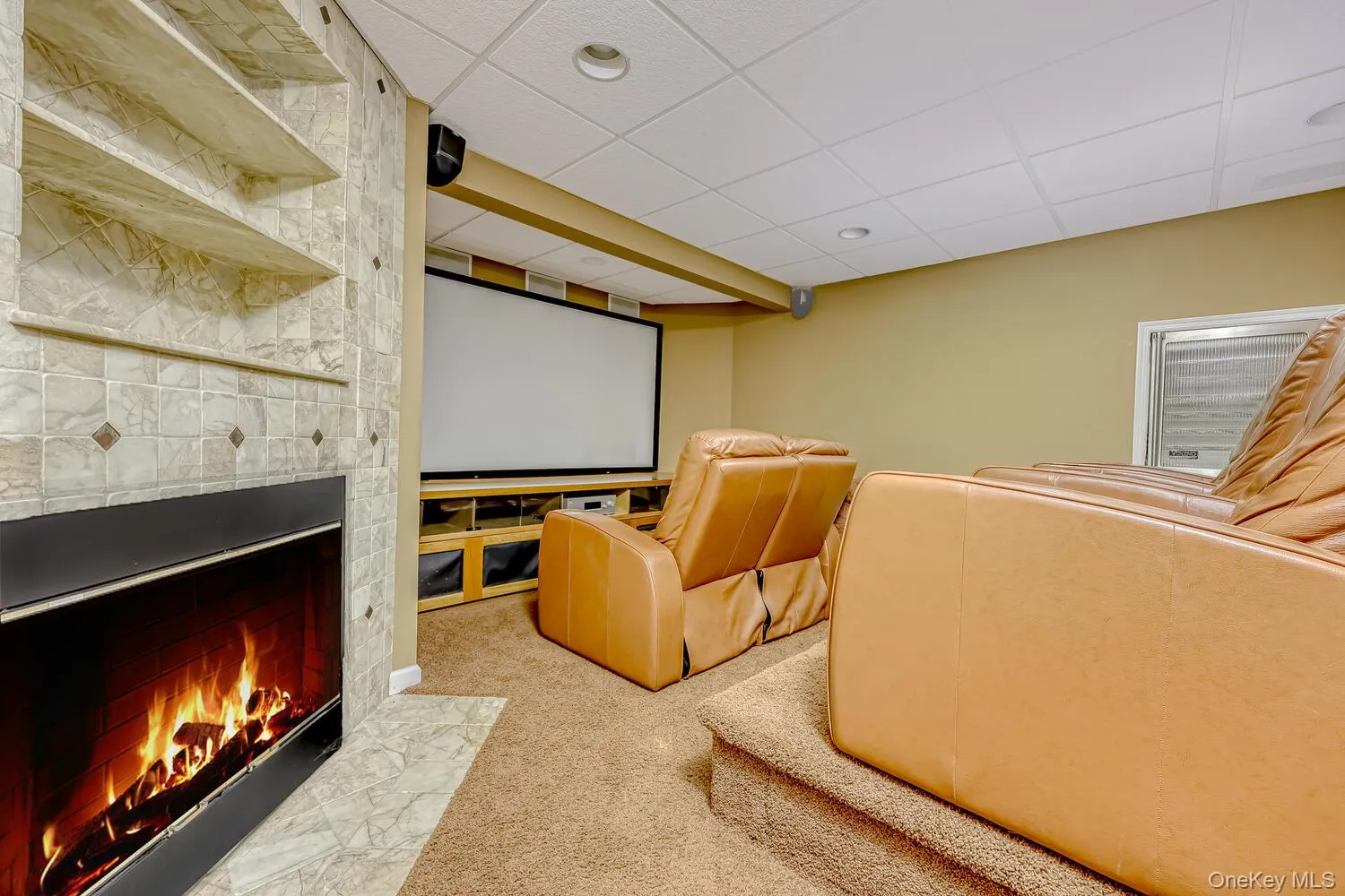 Cinema featuring light colored carpet, a fireplace with flush hearth, and a drop ceiling Cinema featuring light colored carpet, a fireplace with flush hearth, and a drop ceiling