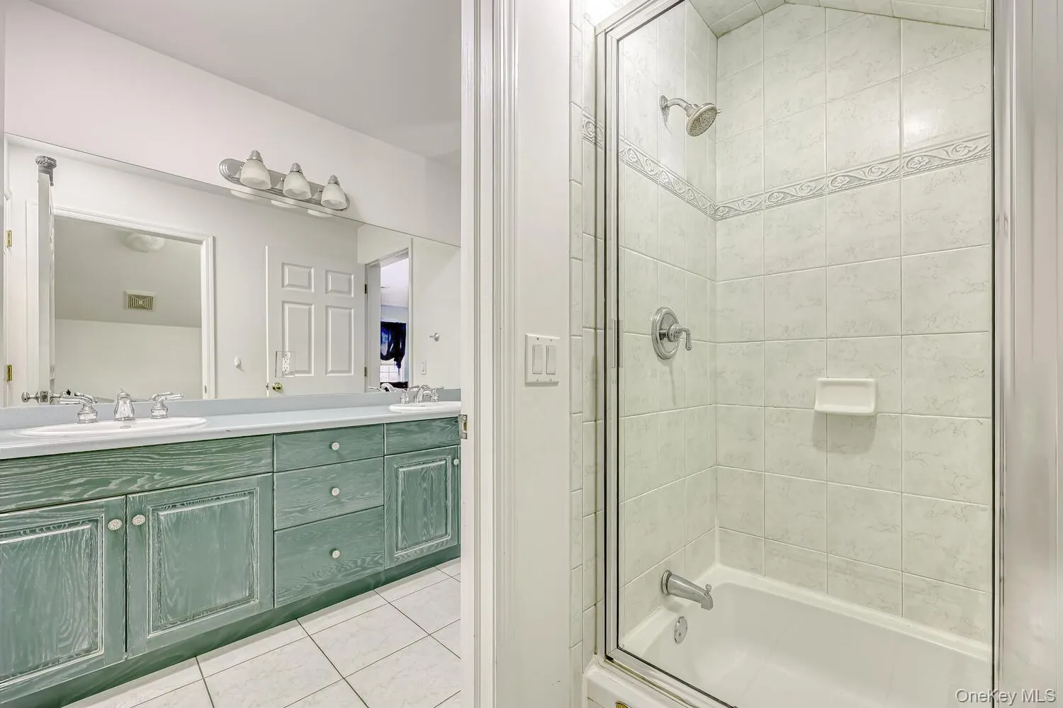 Full bath featuring light tile patterned floors, double vanity, and washtub / shower combination Full bath featuring light tile patterned floors, double vanity, and washtub / shower combination