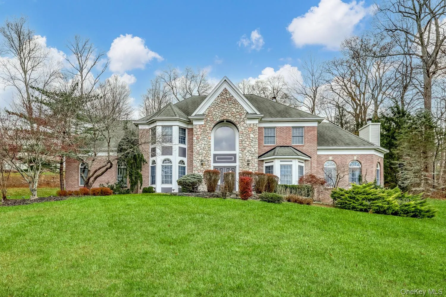 View of front of home featuring a front yard, a shingled roof, a chimney, stone siding, and brick siding View of front of home featuring a front yard, a shingled roof, a chimney, stone siding, and brick siding
