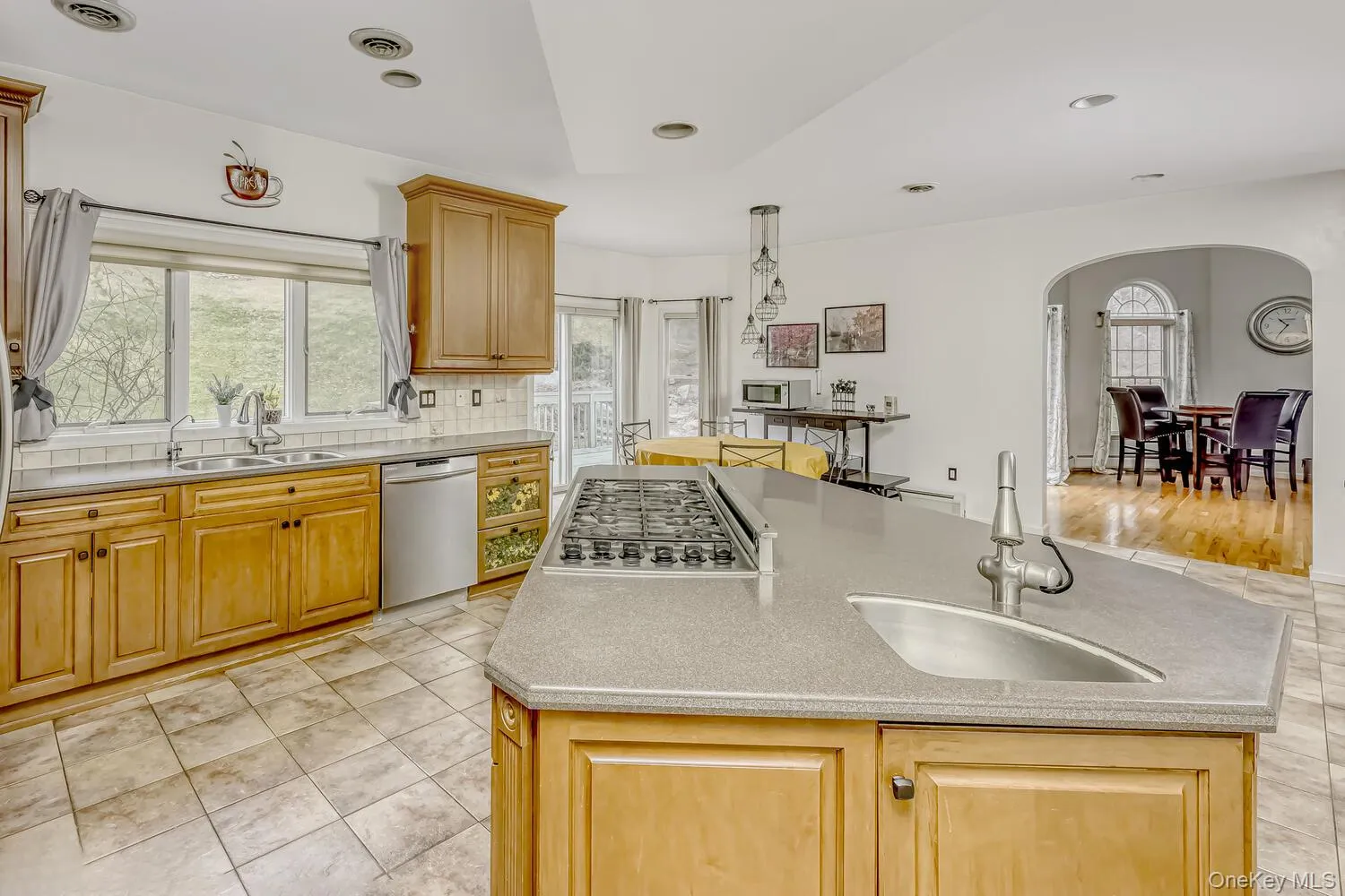 Kitchen with decorative backsplash, light tile patterned floors, appliances with stainless steel finishes, a center island, and recessed lighting Kitchen with decorative backsplash, light tile patterned floors, appliances with stainless steel finishes, a center island, and recessed lighting