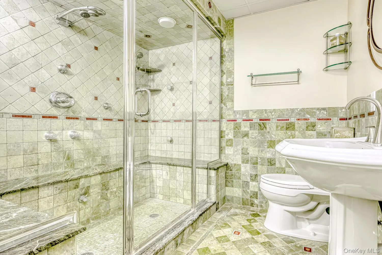 Bathroom featuring tile walls, light tile patterned flooring, a shower stall, and a wainscoted wall Bathroom featuring tile walls, light tile patterned flooring, a shower stall, and a wainscoted wall