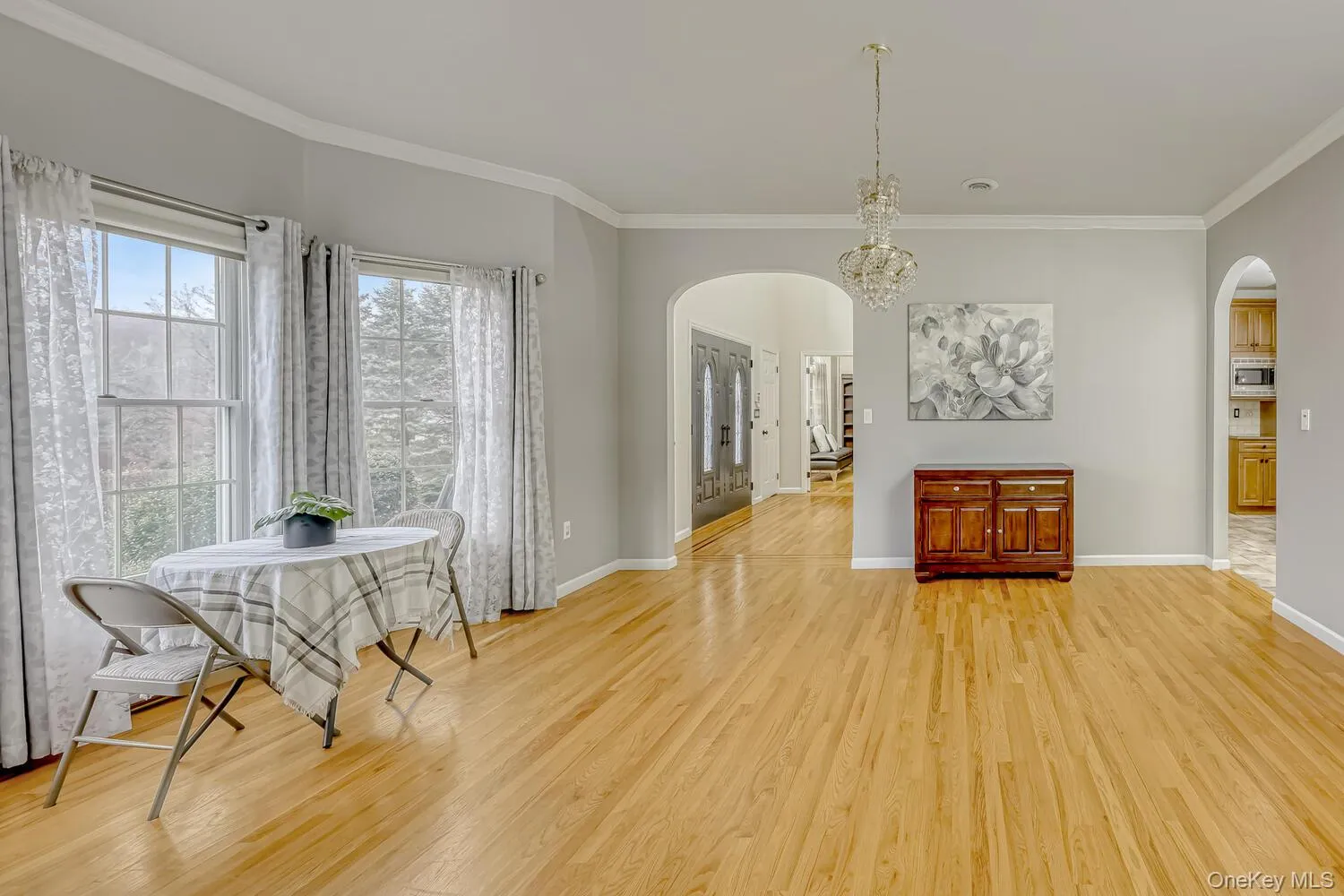 Dining space featuring ornamental molding, arched walkways, and light wood finished floors Dining space featuring ornamental molding, arched walkways, and light wood finished floors