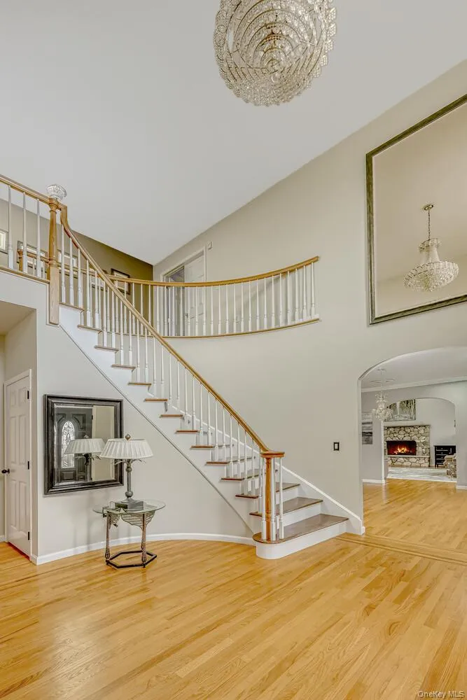 Stairway with a high ceiling, wood finished floors, arched walkways, and a warm lit fireplace Stairway with a high ceiling, wood finished floors, arched walkways, and a warm lit fireplace