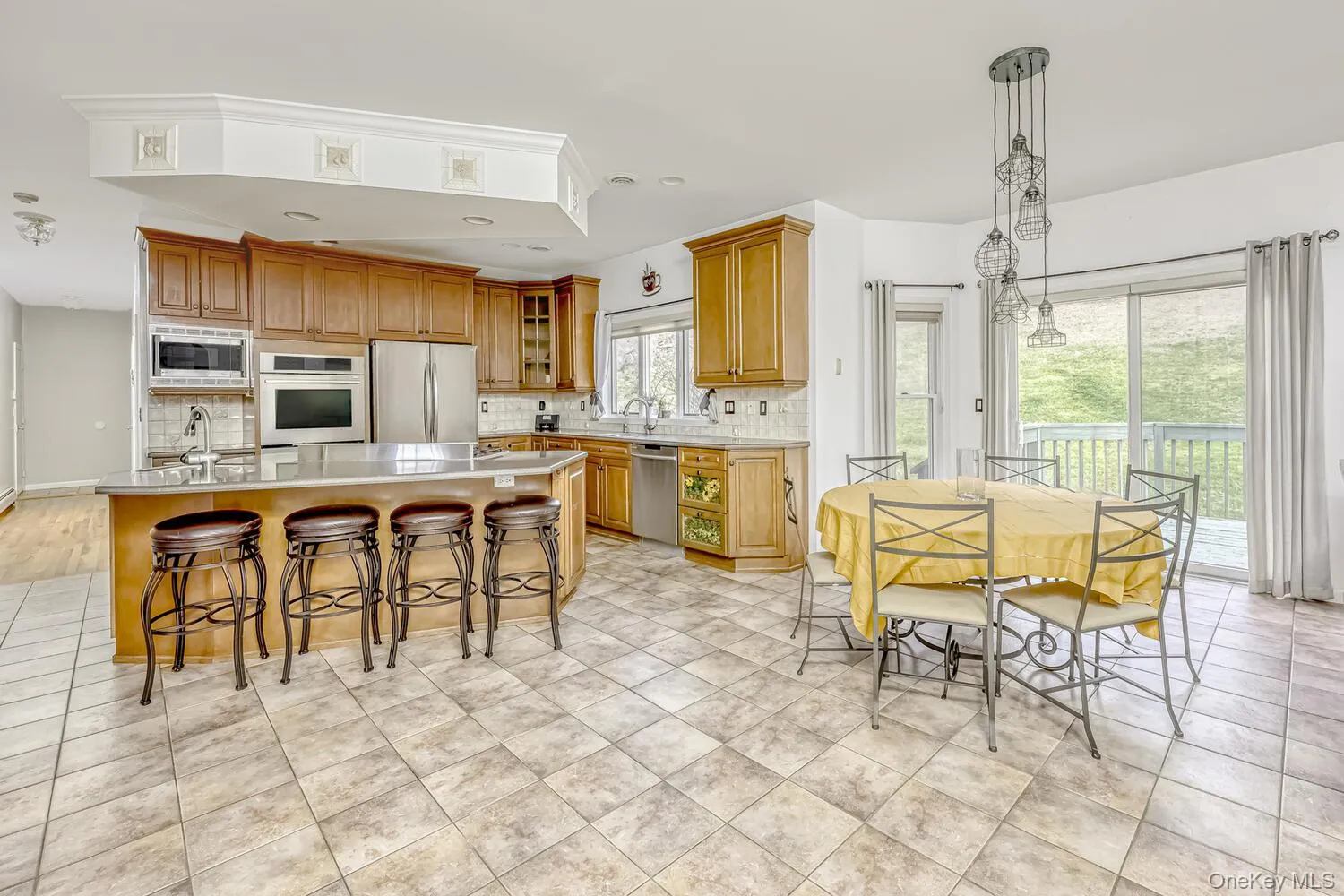 Kitchen featuring decorative backsplash, a kitchen bar, an island with sink, decorative light fixtures, and appliances with stainless steel finishes Kitchen featuring decorative backsplash, a kitchen bar, an island with sink, decorative light fixtures, and appliances with stainless steel finishes