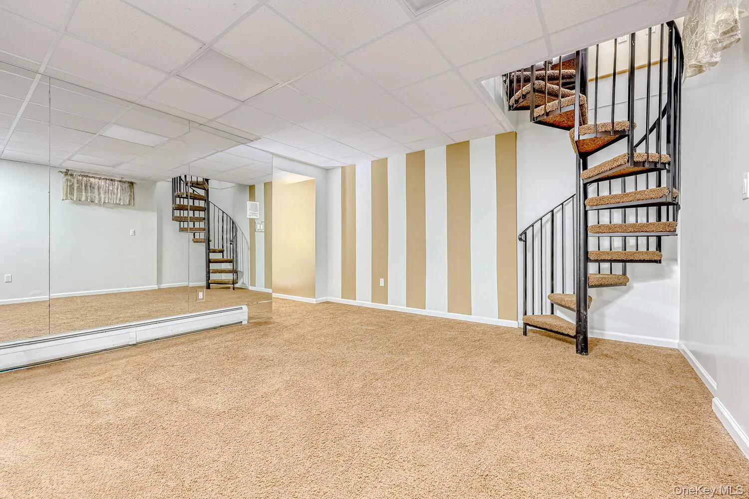 Finished basement with stairway, carpet flooring, a paneled ceiling, and wallpapered walls Finished basement with stairway, carpet flooring, a paneled ceiling, and wallpapered walls