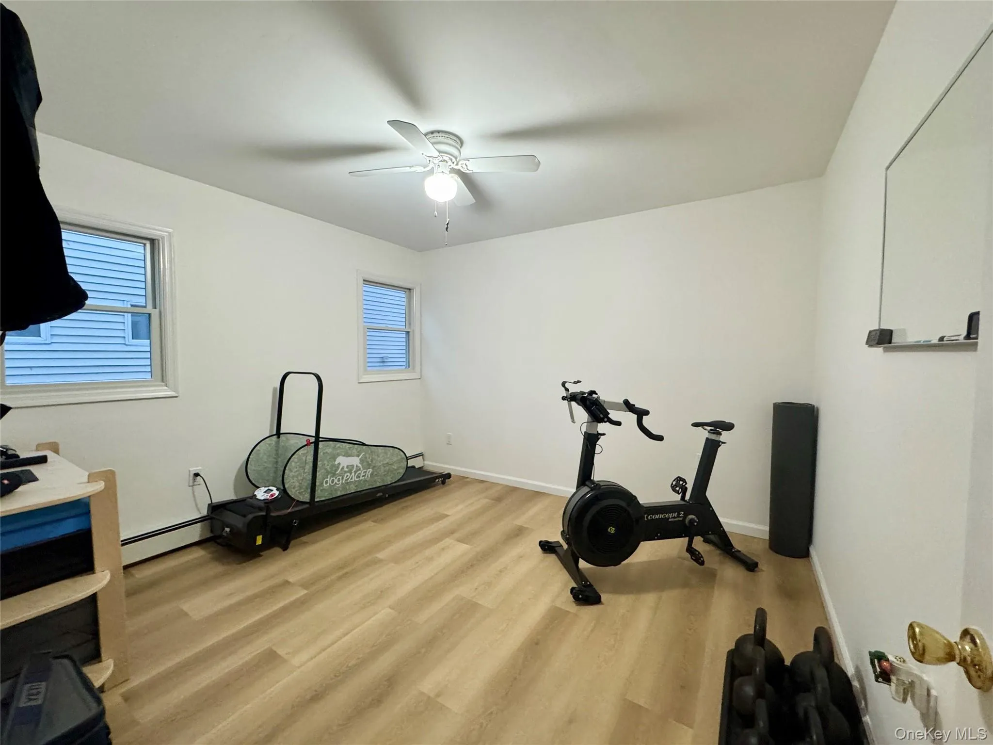 Bedroom being used as an Exercise area with light wood finished floors, baseboard heating, and ceiling fan Bedroom being used as an Exercise area with light wood finished floors, baseboard heating, and ceiling fan