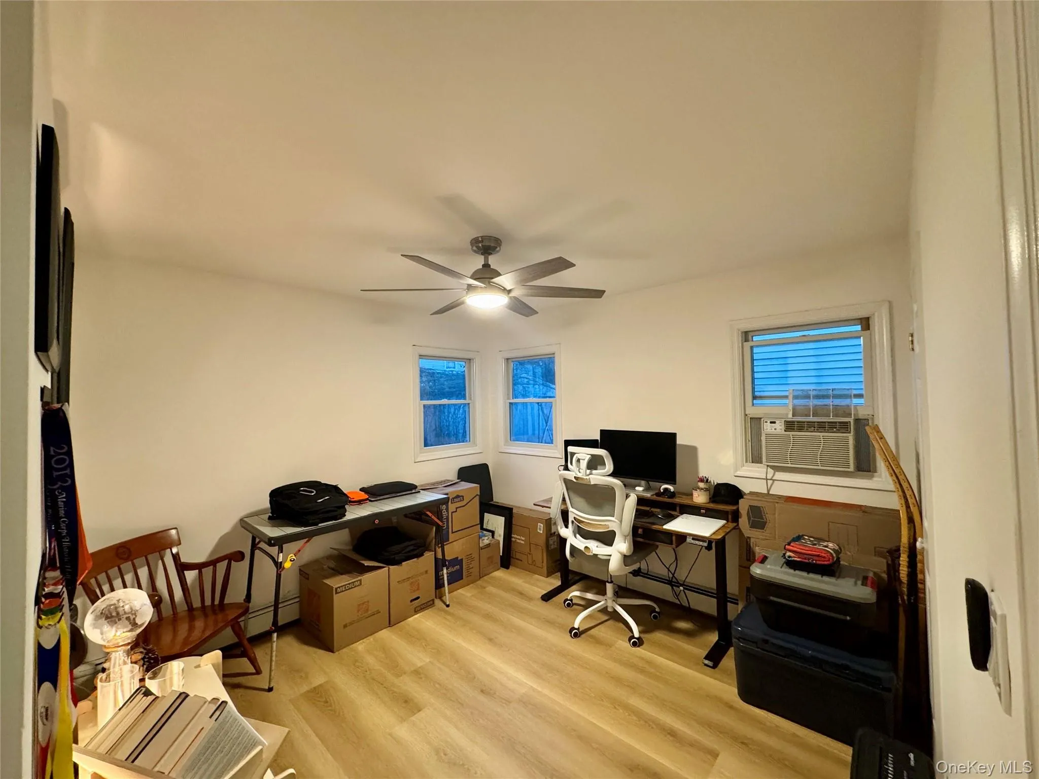 Bedroom being used as a Home office featuring light wood finished floors, ceiling fan, cooling unit, and a baseboard radiator Bedroom being used as a Home office featuring light wood finished floors, ceiling fan, cooling unit, and a baseboard radiator