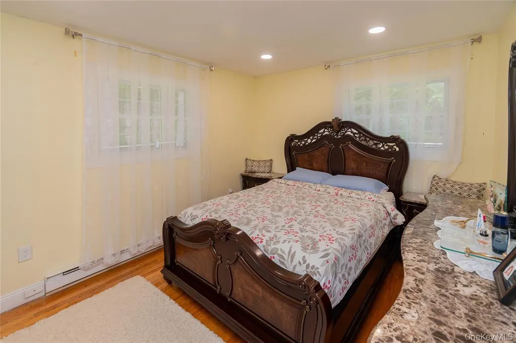 Bedroom with wood finished floors, recessed lighting, and a baseboard radiator Bedroom with wood finished floors, recessed lighting, and a baseboard radiator