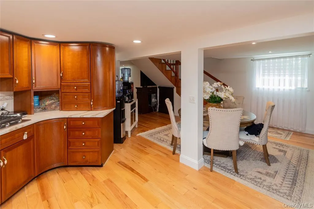 Kitchen with brown cabinets, light wood-style floors, recessed lighting, stainless steel gas cooktop, and light stone counters Kitchen with brown cabinets, light wood-style floors, recessed lighting, stainless steel gas cooktop, and light stone counters