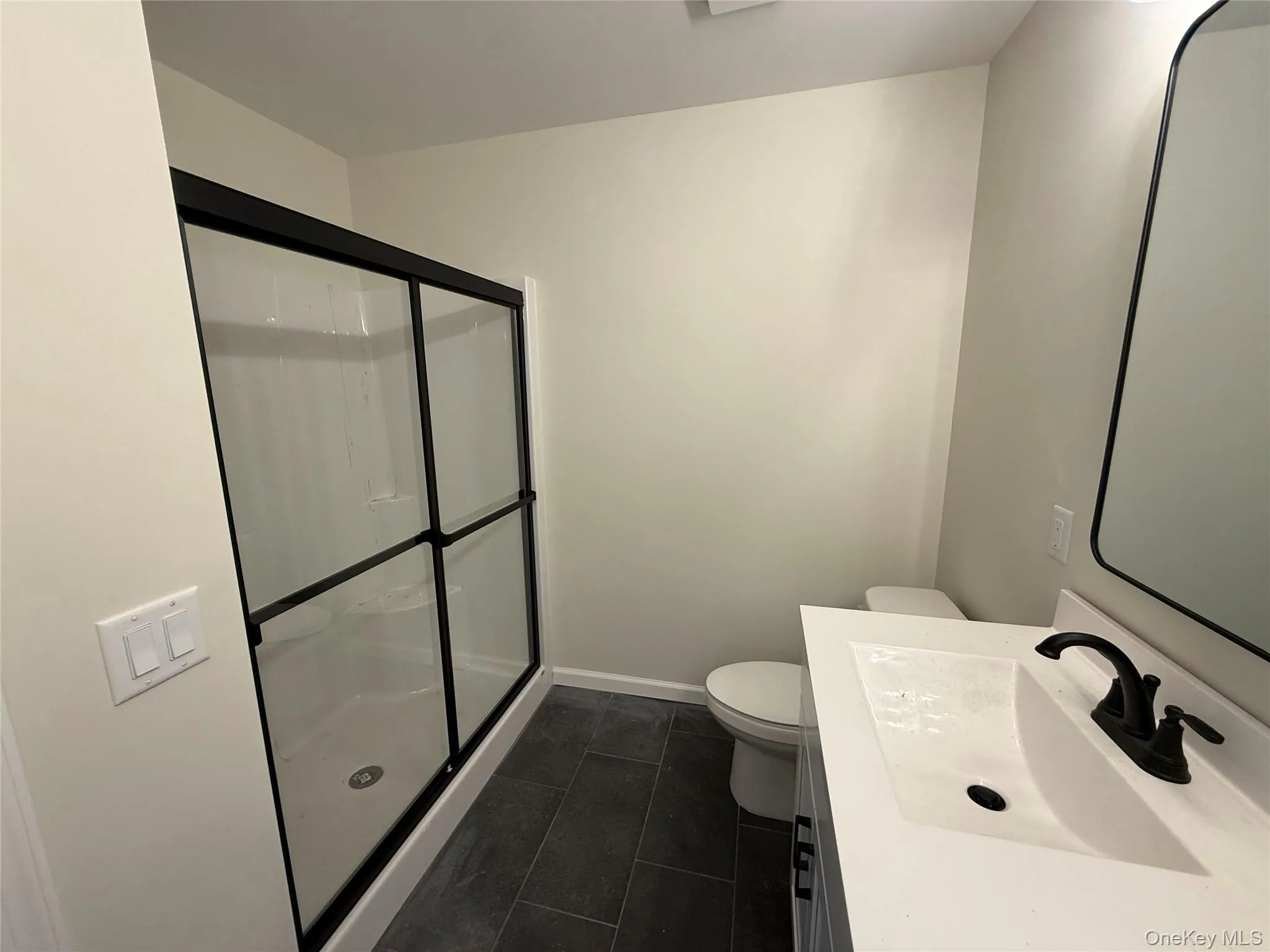 Full bath featuring a stall shower, vanity, and dark tile patterned floors Full bath featuring a stall shower, vanity, and dark tile patterned floors