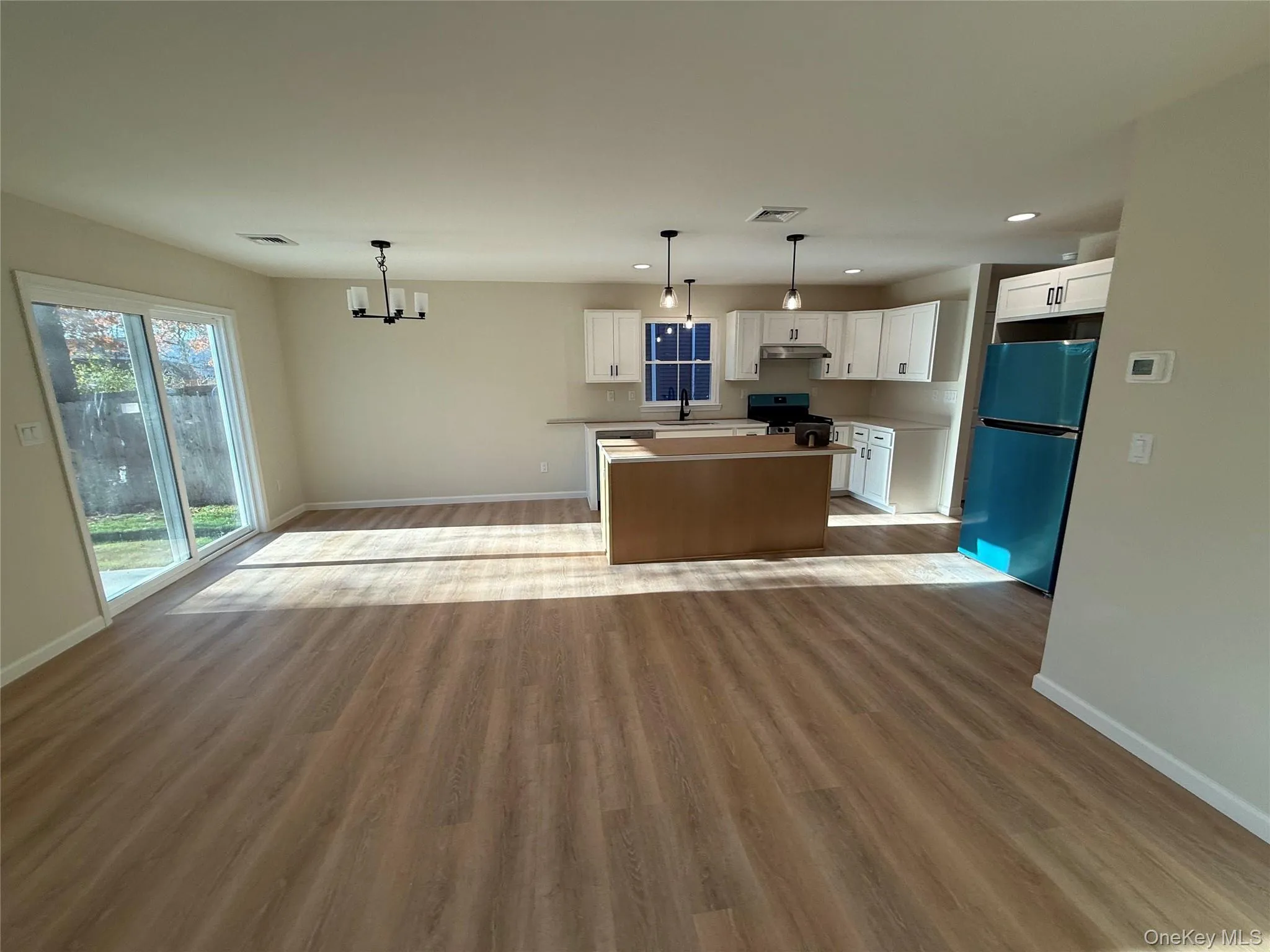 Kitchen with a kitchen island, decorative light fixtures, white cabinetry, open floor plan, and dark wood finished floors Kitchen with a kitchen island, decorative light fixtures, white cabinetry, open floor plan, and dark wood finished floors