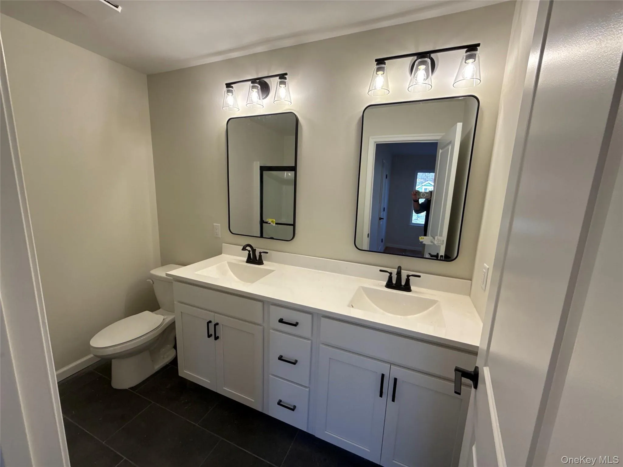 Full bathroom featuring double vanity and dark tile patterned floors Full bathroom featuring double vanity and dark tile patterned floors