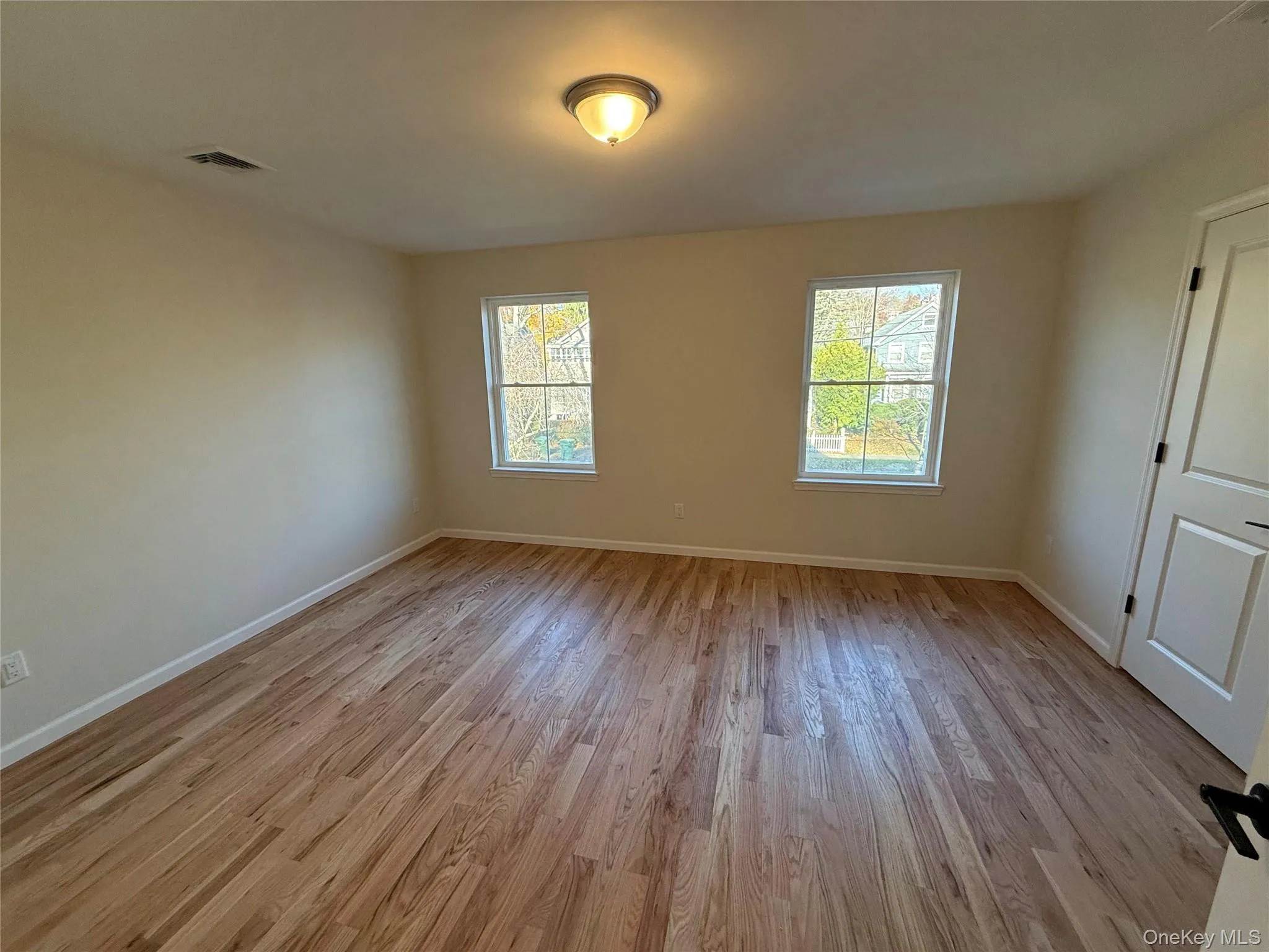 Empty room featuring healthy amount of natural light and light wood-style floors Empty room featuring healthy amount of natural light and light wood-style floors
