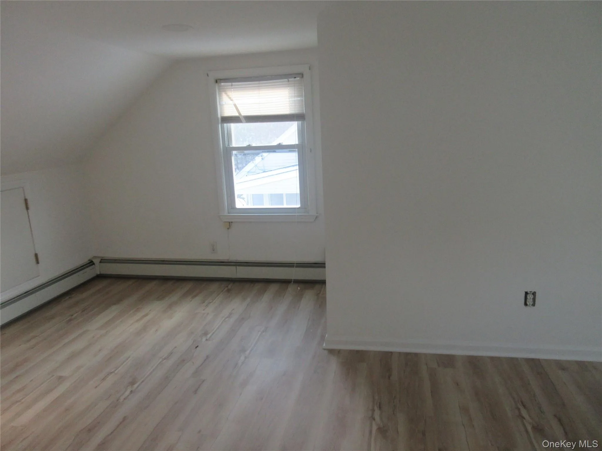 Bonus room with light wood-style floors, vaulted ceiling, and baseboard heating Bonus room with light wood-style floors, vaulted ceiling, and baseboard heating