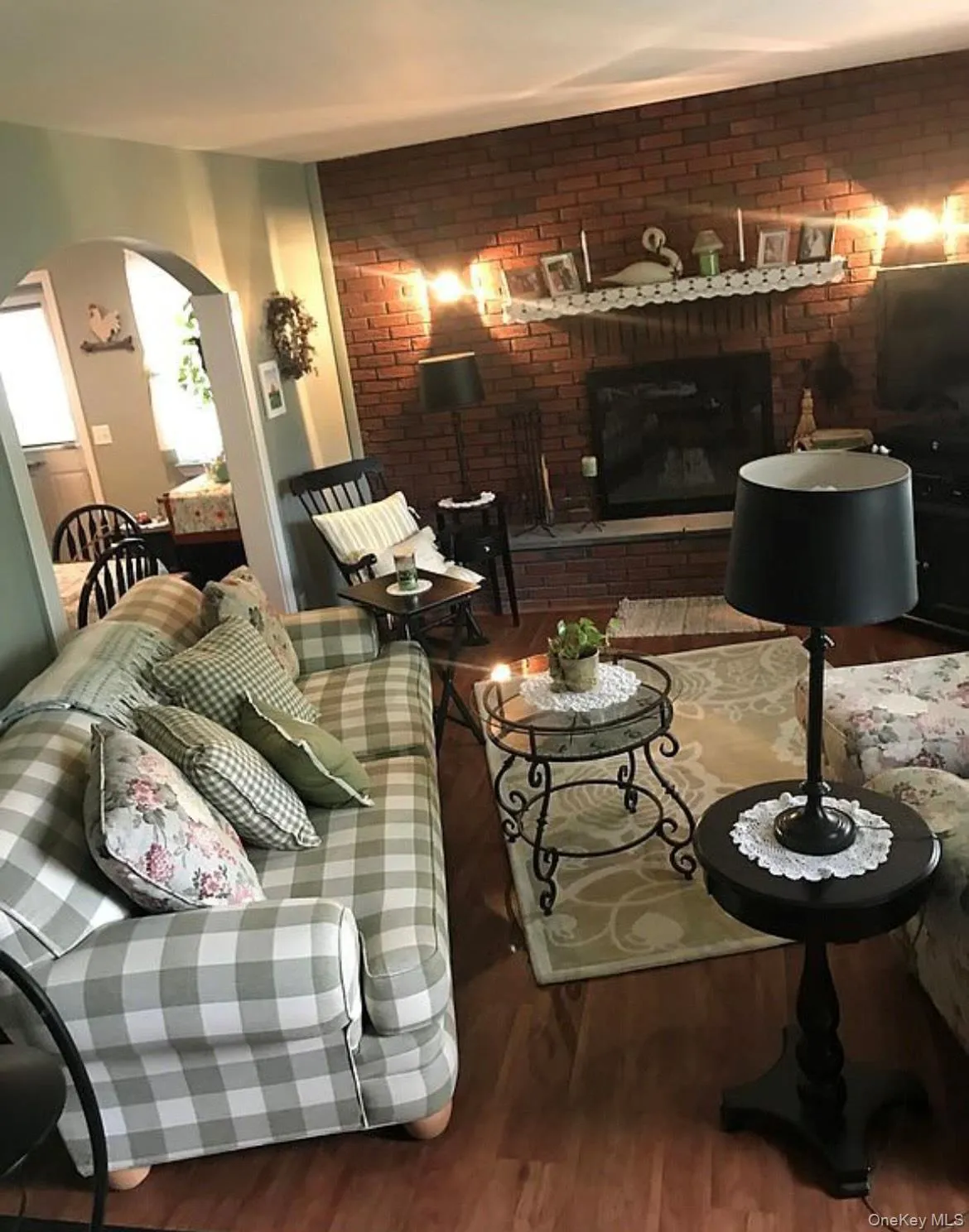 Living room with wood finished floors, arched walkways, and brick wall Living room with wood finished floors, arched walkways, and brick wall