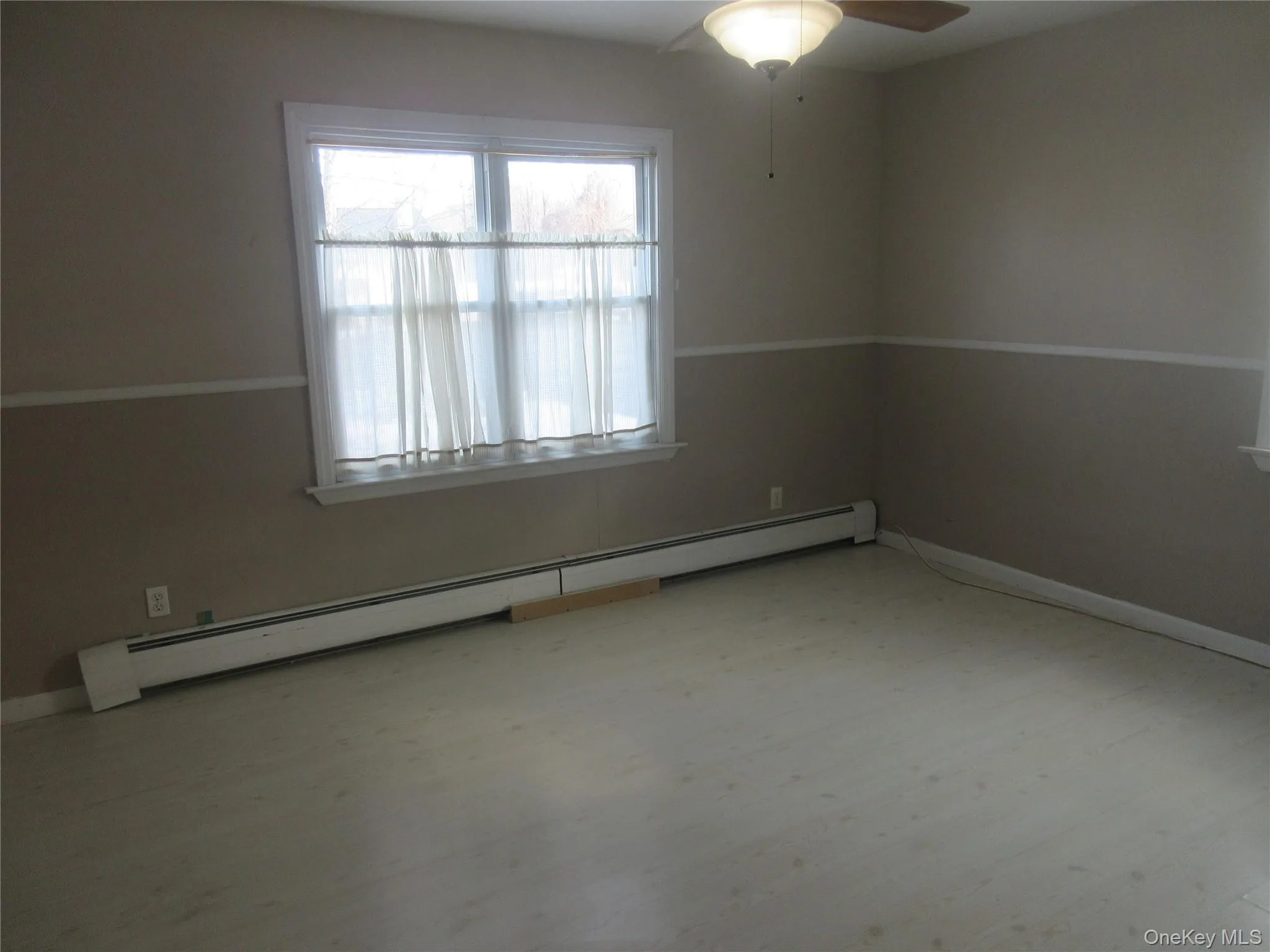 Spare room featuring baseboard heating, light wood-type flooring, and a ceiling fan Spare room featuring baseboard heating, light wood-type flooring, and a ceiling fan