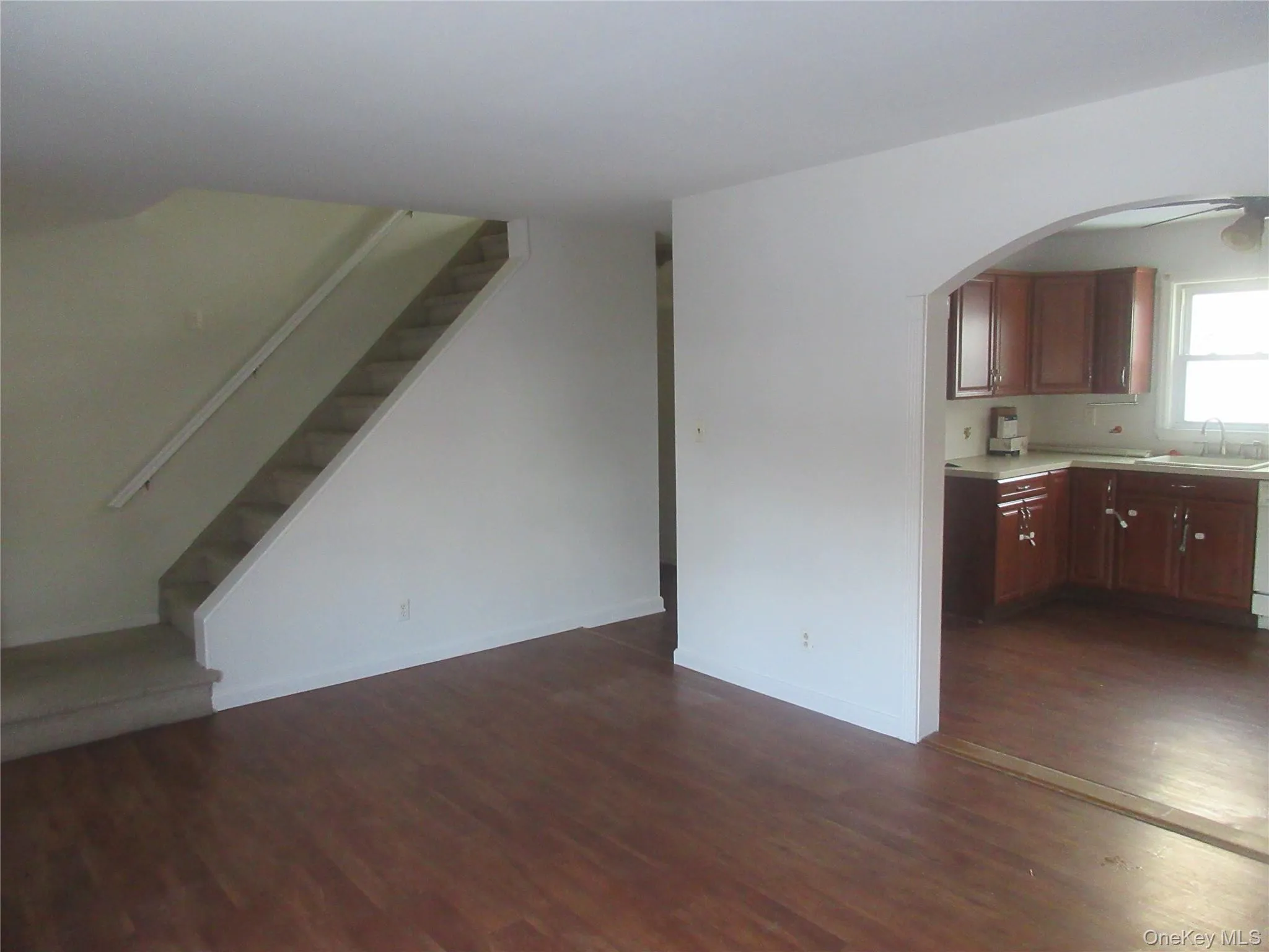 Unfurnished living room with dark wood-style floors, stairway, and arched walkways Unfurnished living room with dark wood-style floors, stairway, and arched walkways