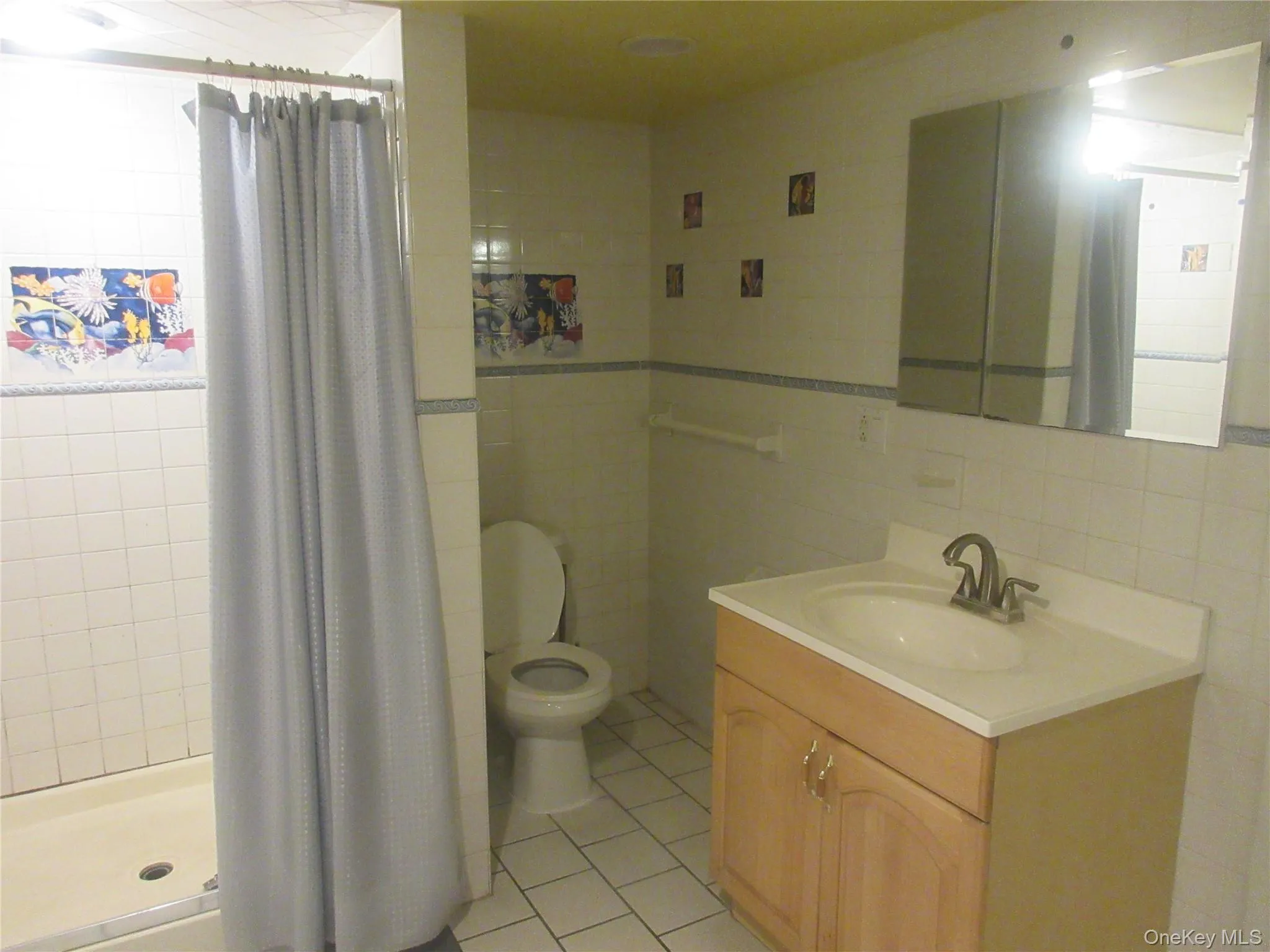 Full bath with light tile patterned floors, a shower stall, vanity, and tile walls Full bath with light tile patterned floors, a shower stall, vanity, and tile walls