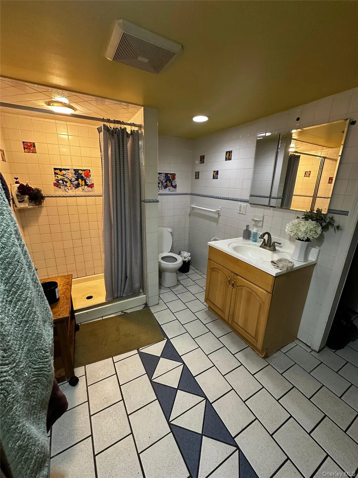 Bathroom with vanity, light tile patterned flooring, tile walls, and a stall shower Bathroom with vanity, light tile patterned flooring, tile walls, and a stall shower