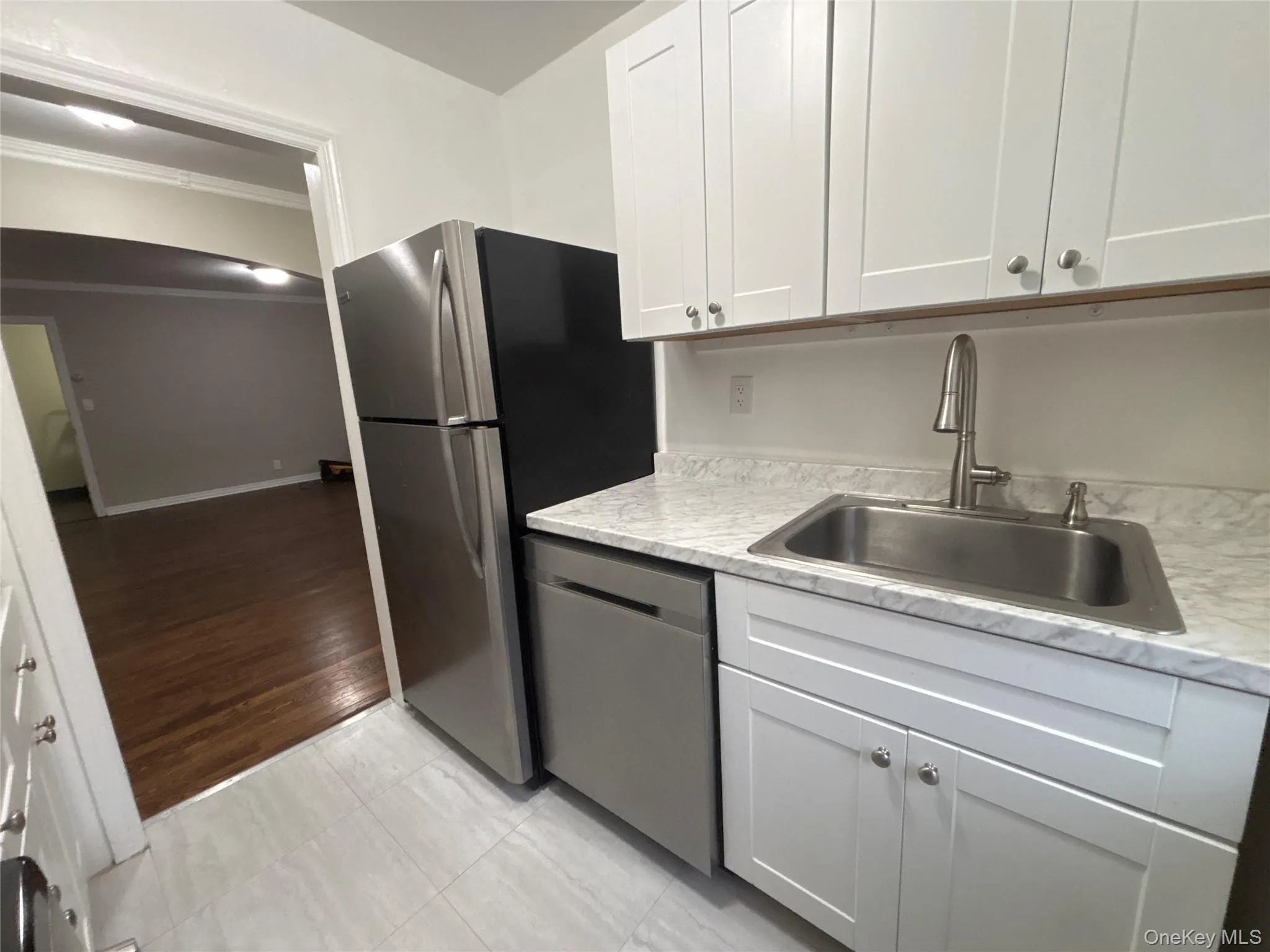 Kitchen featuring white cabinets, light countertops, stainless steel appliances, light tile patterned floors, and crown molding Kitchen featuring white cabinets, light countertops, stainless steel appliances, light tile patterned floors, and crown molding