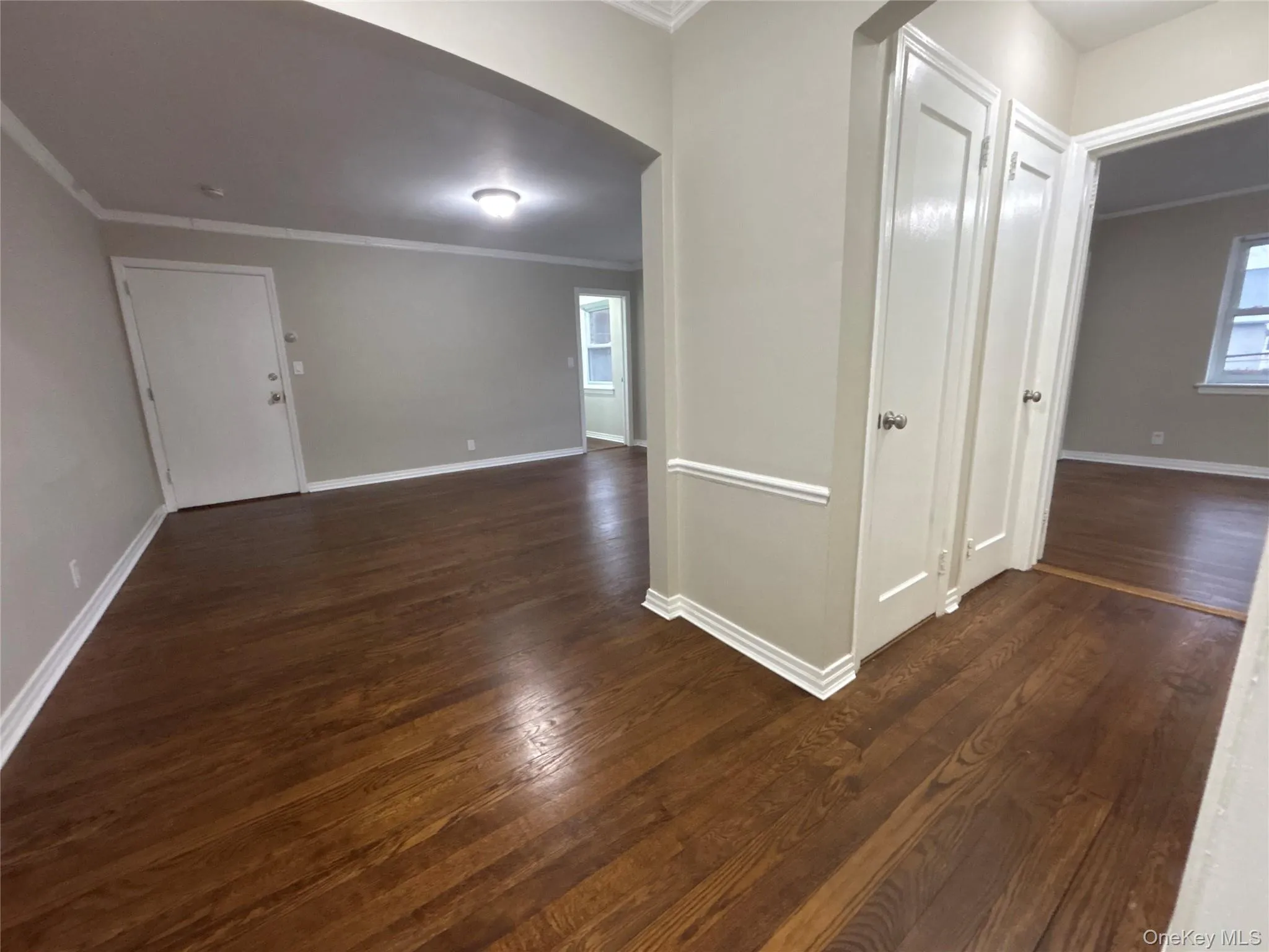 Corridor with ornamental molding, dark wood-style floors, arched walkways, and plenty of natural light Corridor with ornamental molding, dark wood-style floors, arched walkways, and plenty of natural light