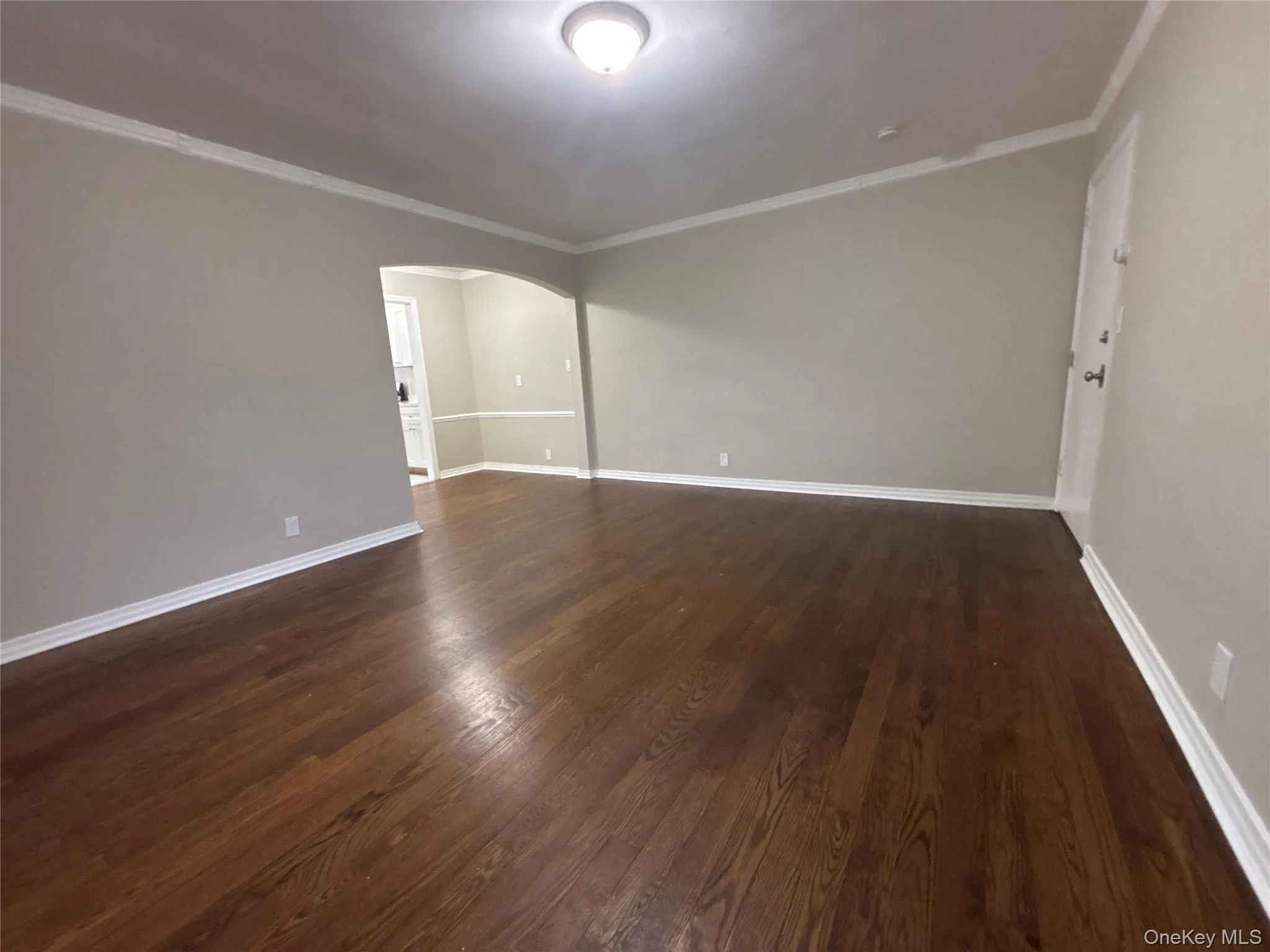 Unfurnished room with arched walkways, crown molding, and dark wood-type flooring Unfurnished room with arched walkways, crown molding, and dark wood-type flooring