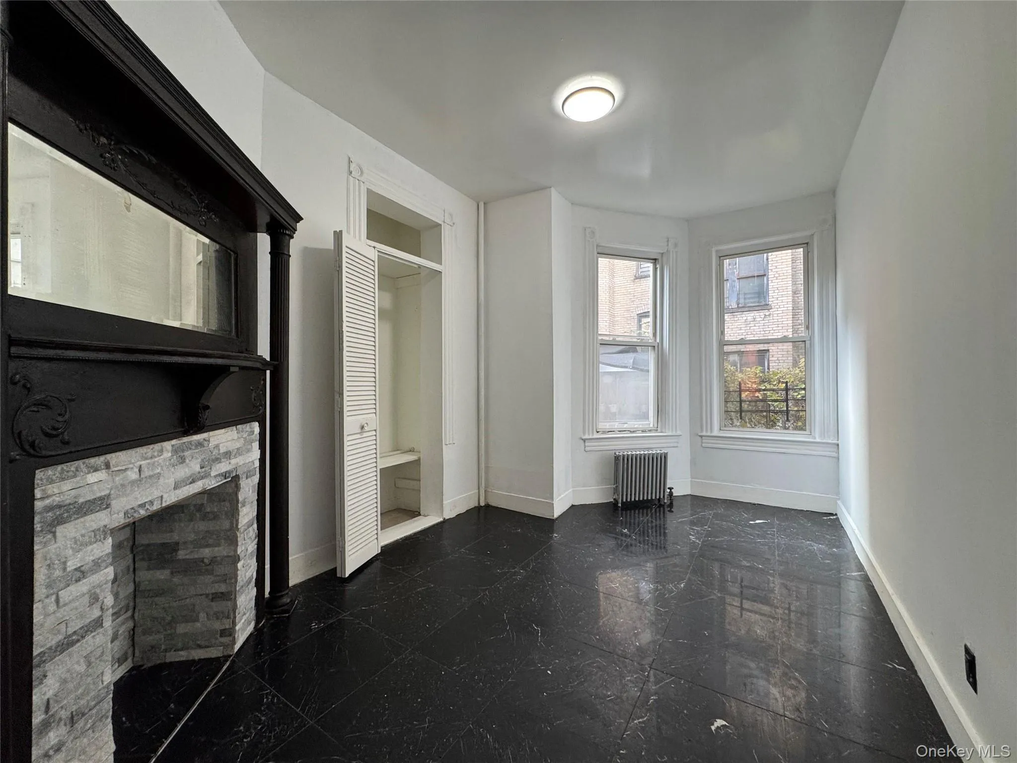 Unfurnished living room with radiator, a stone fireplace, and granite floors Unfurnished living room with radiator, a stone fireplace, and granite floors
