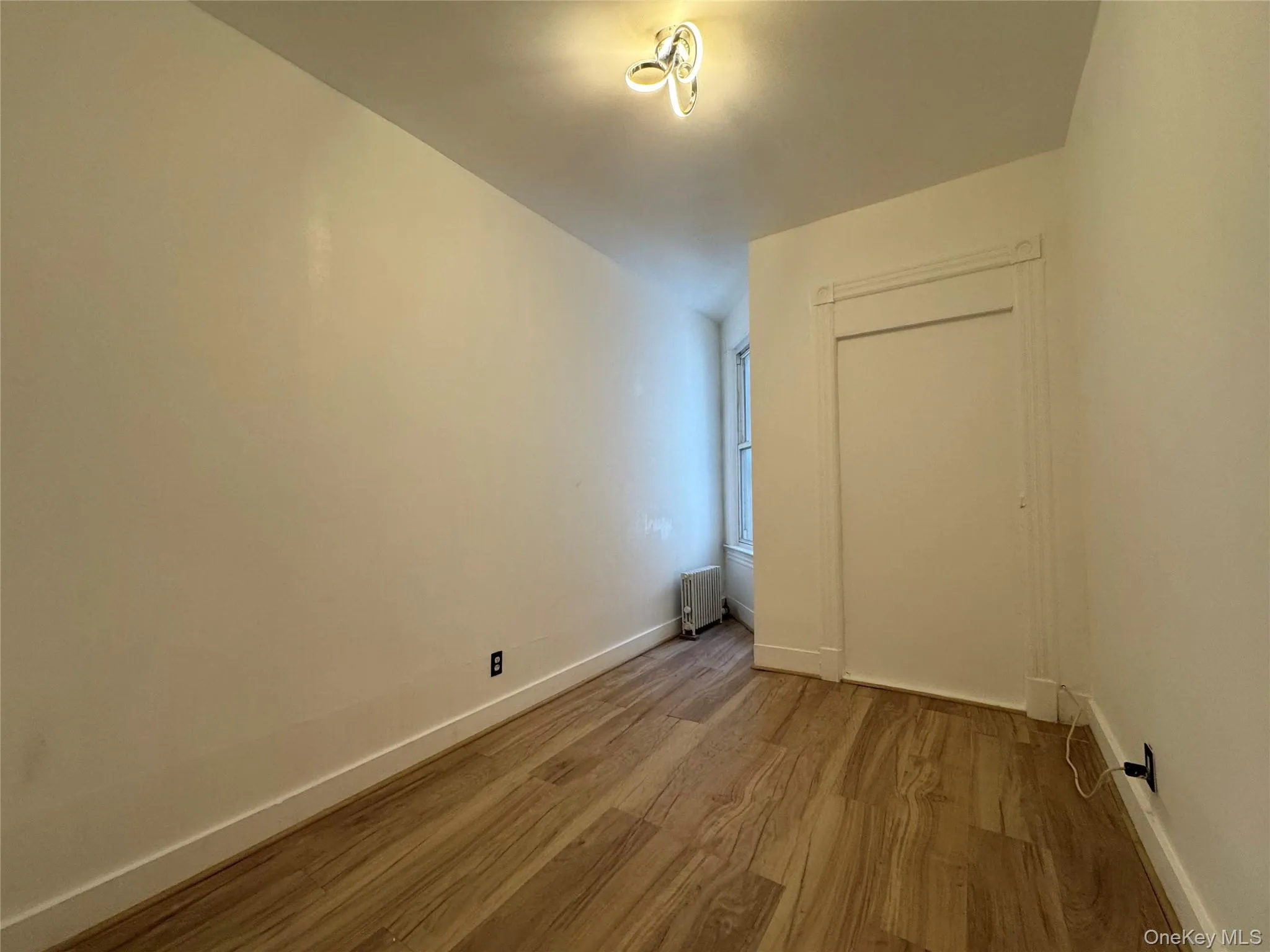 Empty room with wood finished floors and radiator Empty room with wood finished floors and radiator