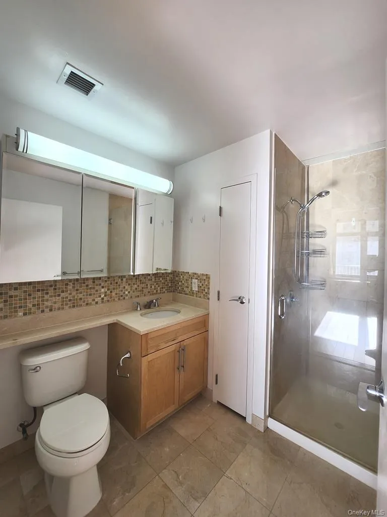 Full bath with vanity, a stall shower, and decorative backsplash Full bath with vanity, a stall shower, and decorative backsplash