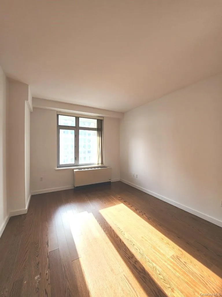 Unfurnished room with wood finished floors and baseboards Unfurnished room with wood finished floors and baseboards