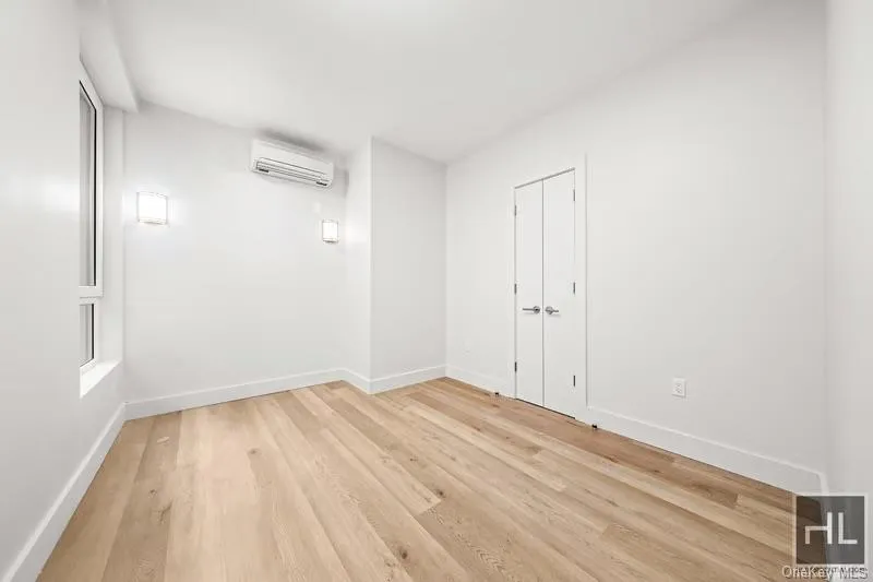 Spare room featuring light wood finished floors and a wall mounted air conditioner Spare room featuring light wood finished floors and a wall mounted air conditioner