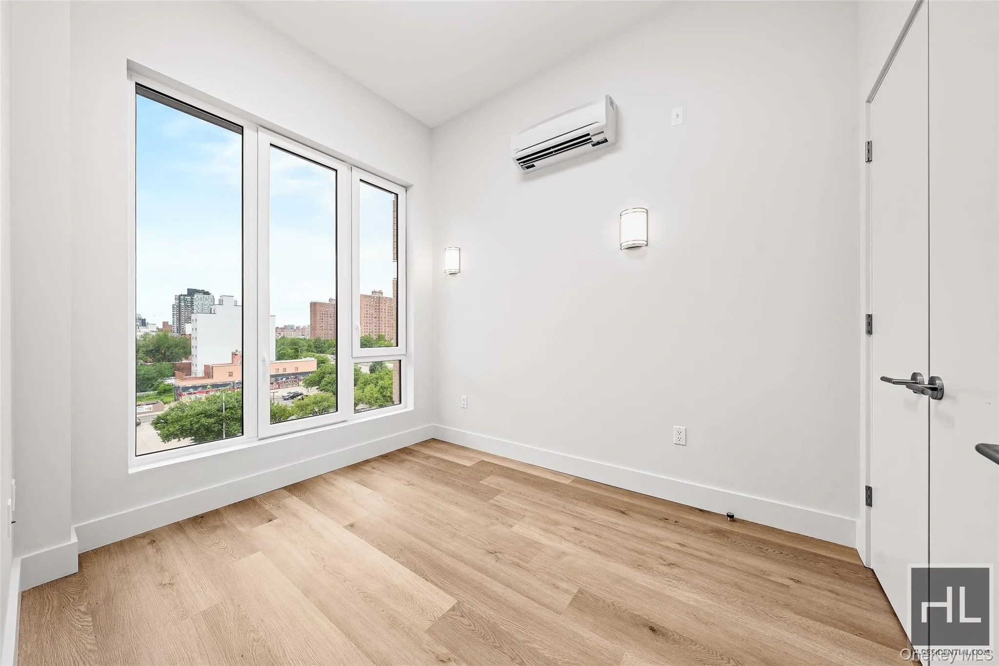 Spare room featuring light wood-style floors, a city view, and a wall mounted AC Spare room featuring light wood-style floors, a city view, and a wall mounted AC