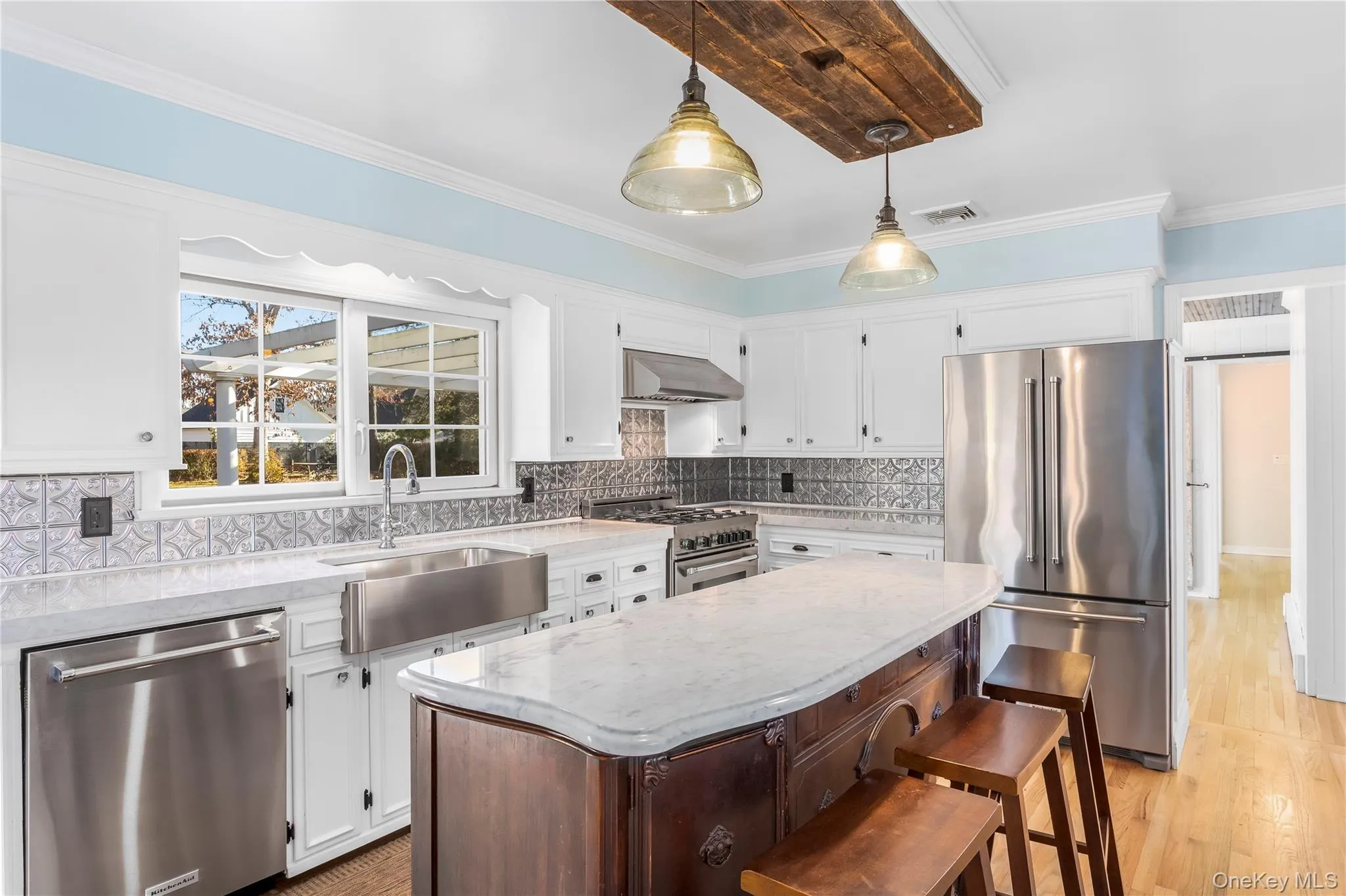 Kitchen featuring high quality appliances, white cabinets, a center island, light stone counters, and crown molding Kitchen featuring high quality appliances, white cabinets, a center island, light stone counters, and crown molding