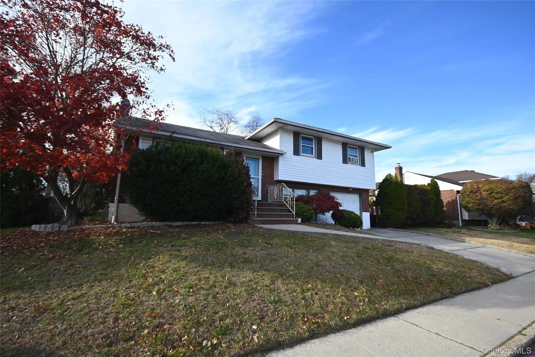 Split level home with brick siding, driveway, a front lawn, and an attached garage Split level home with brick siding, driveway, a front lawn, and an attached garage