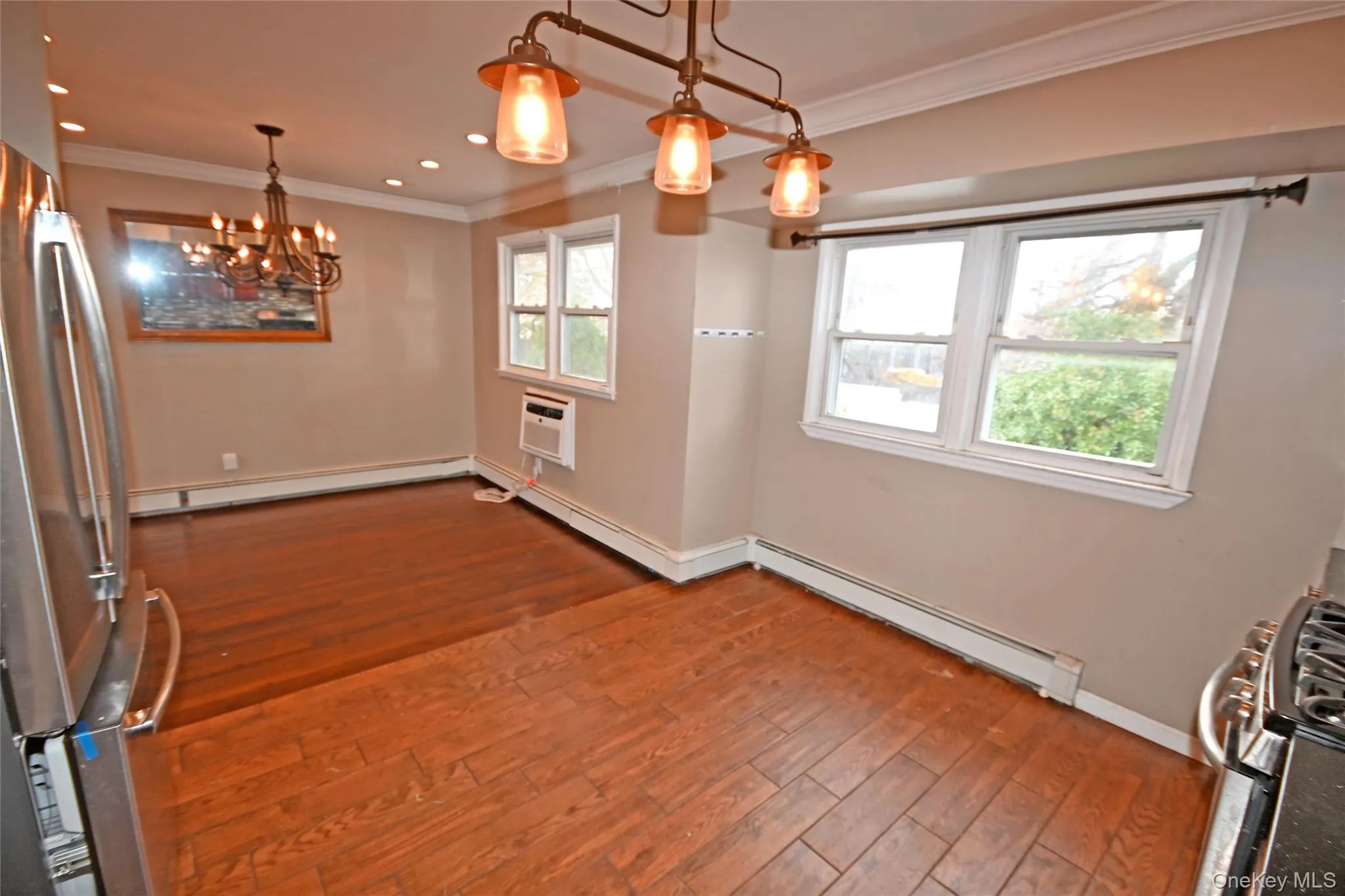 Unfurnished dining area featuring a chandelier, ornamental molding, dark wood-type flooring, a baseboard radiator, and recessed lighting Unfurnished dining area featuring a chandelier, ornamental molding, dark wood-type flooring, a baseboard radiator, and recessed lighting